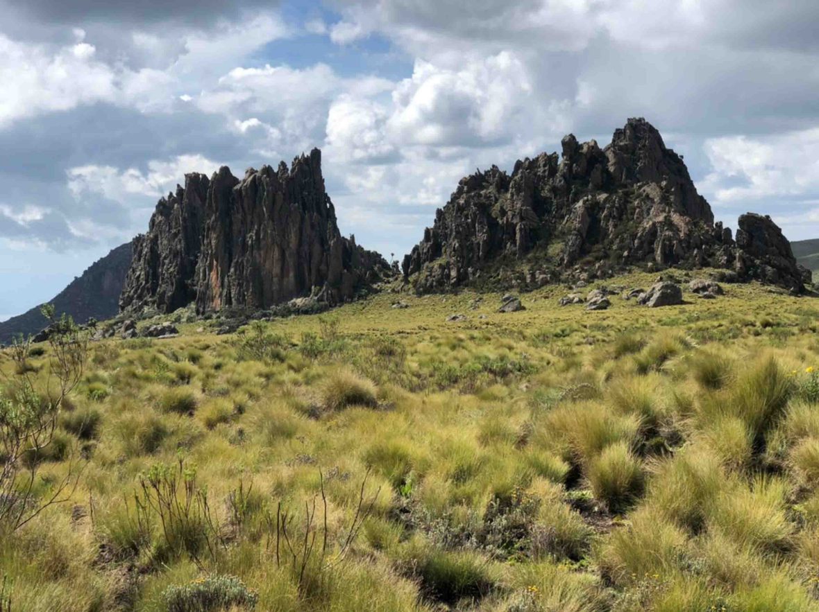 A grassy hill leads to some spiky rock formations.