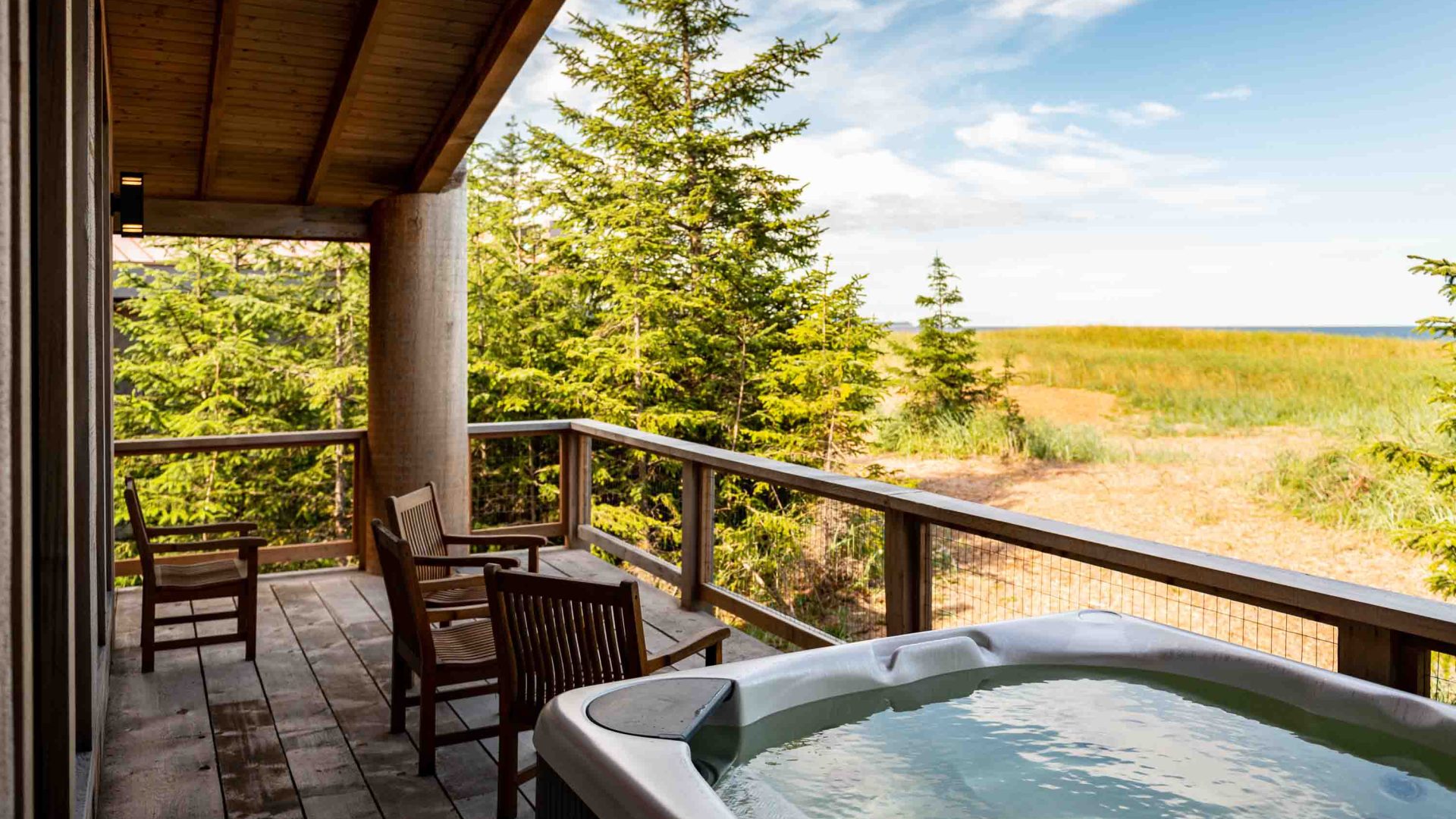 A spa on the deck of a hotel room, which has views of dirt paths and trees.
