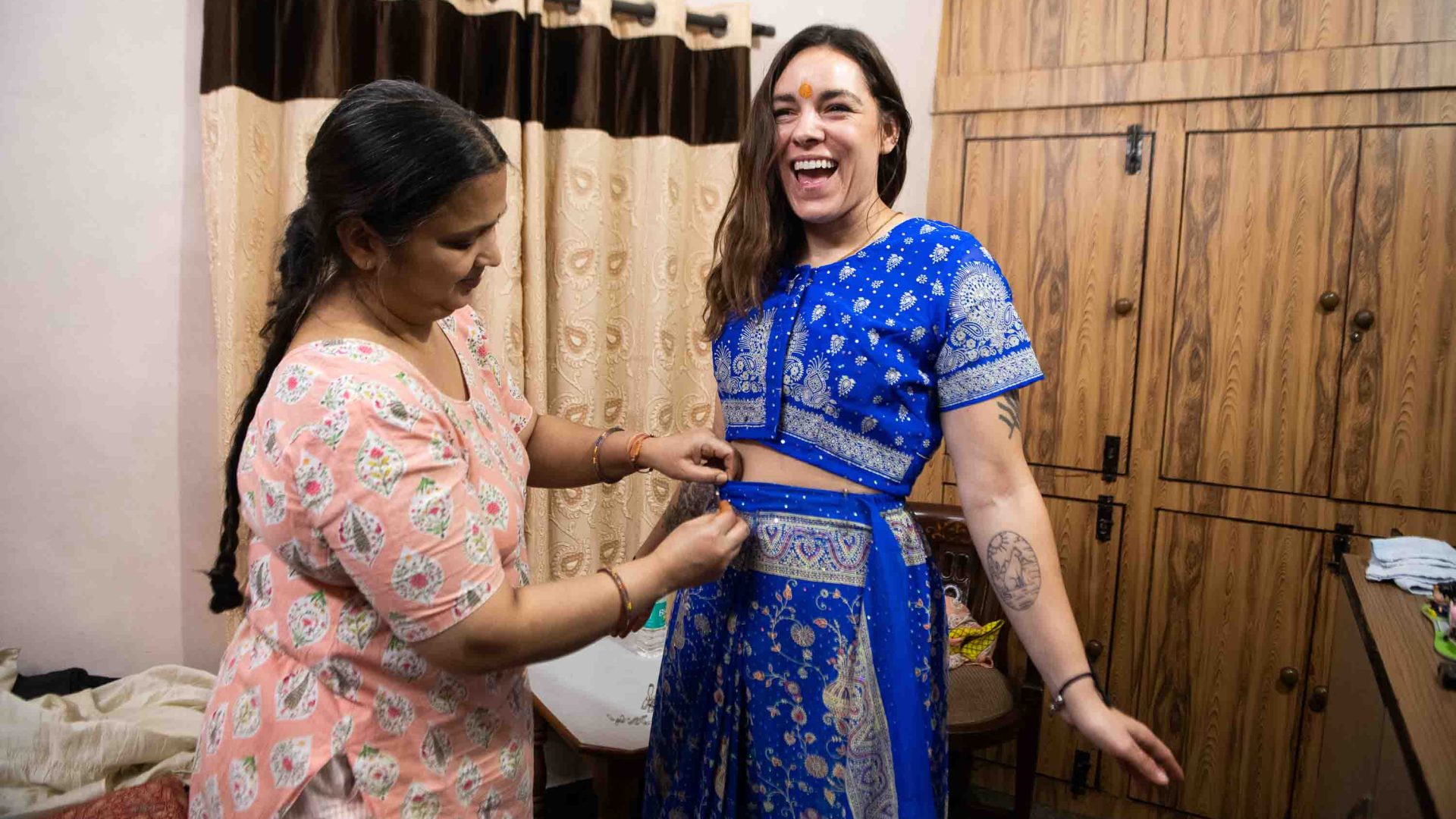 A traveler is taught to tie a sari by a local woman.