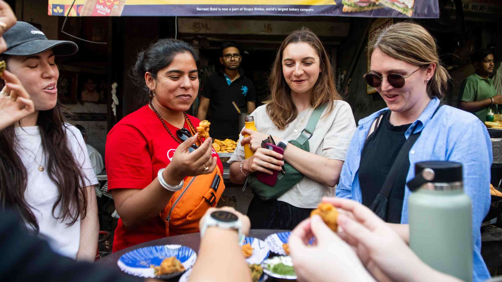 A tour gide and other travelers eat local food in the street.