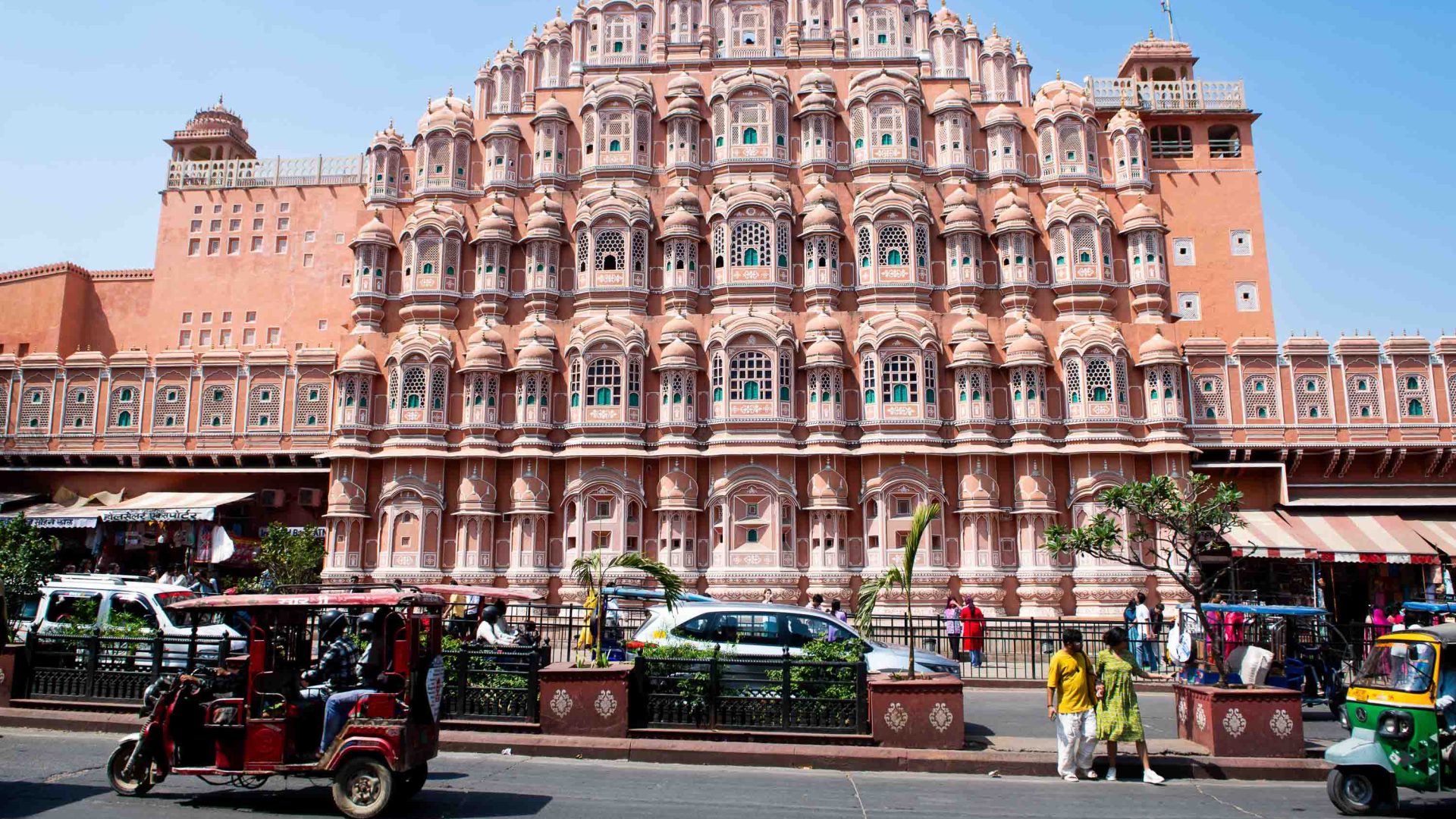 Traffic drives past a pink palace.