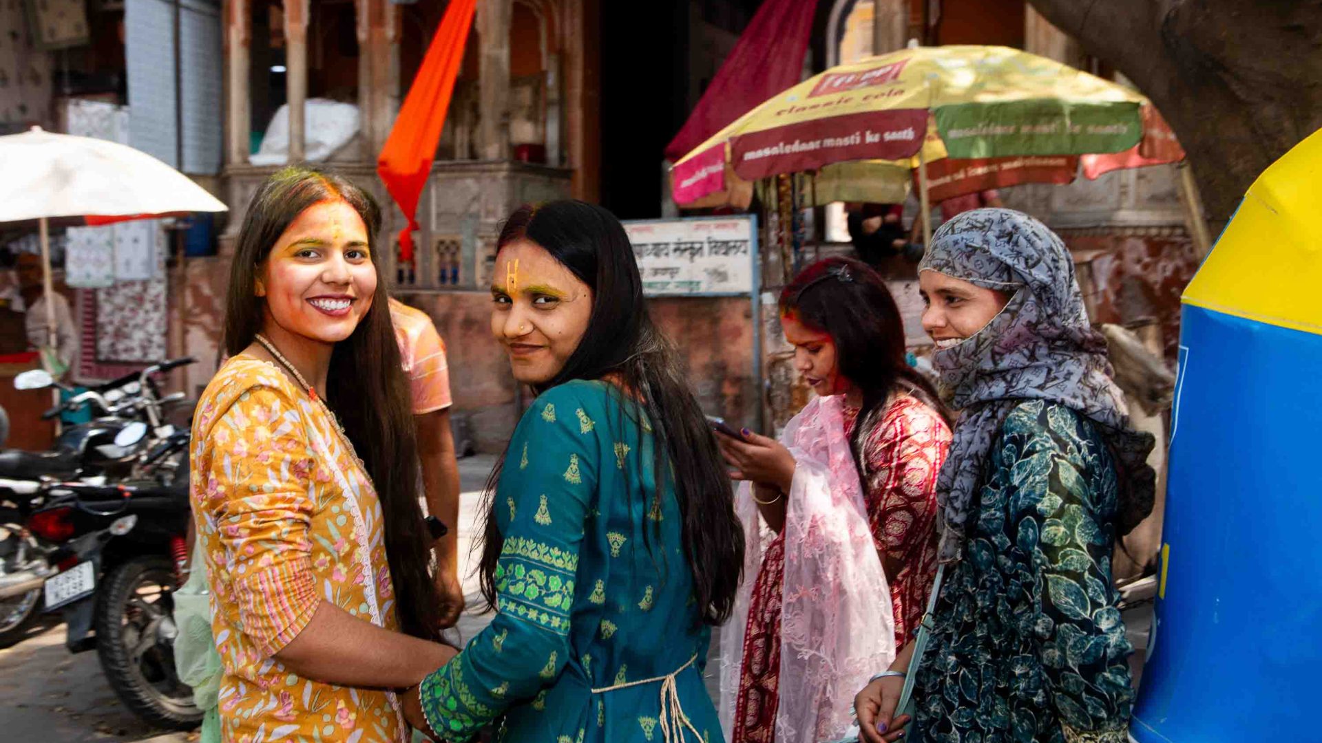 A group of women in Saris look candidly at the camera.