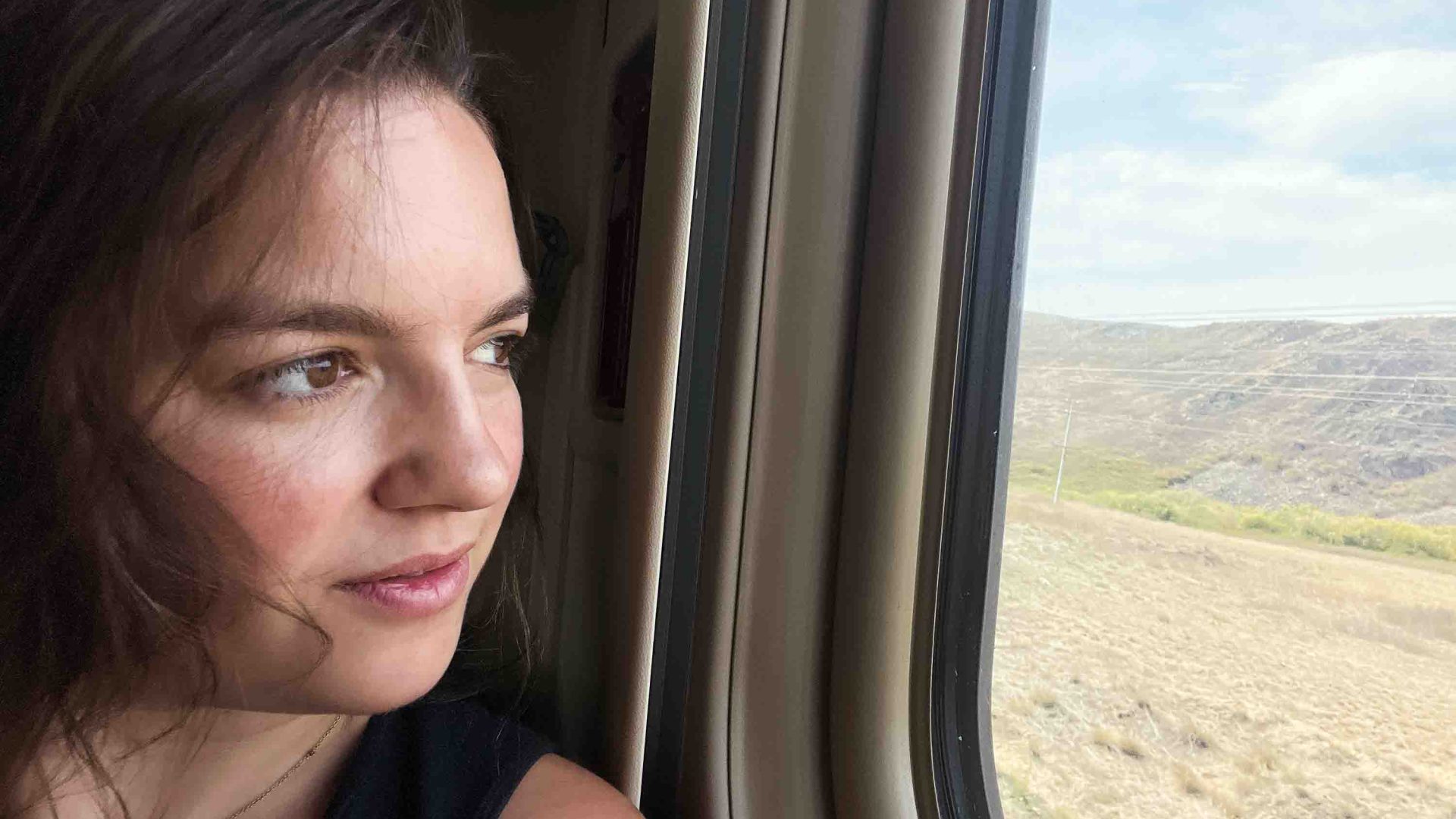 A woman looks out a train window.