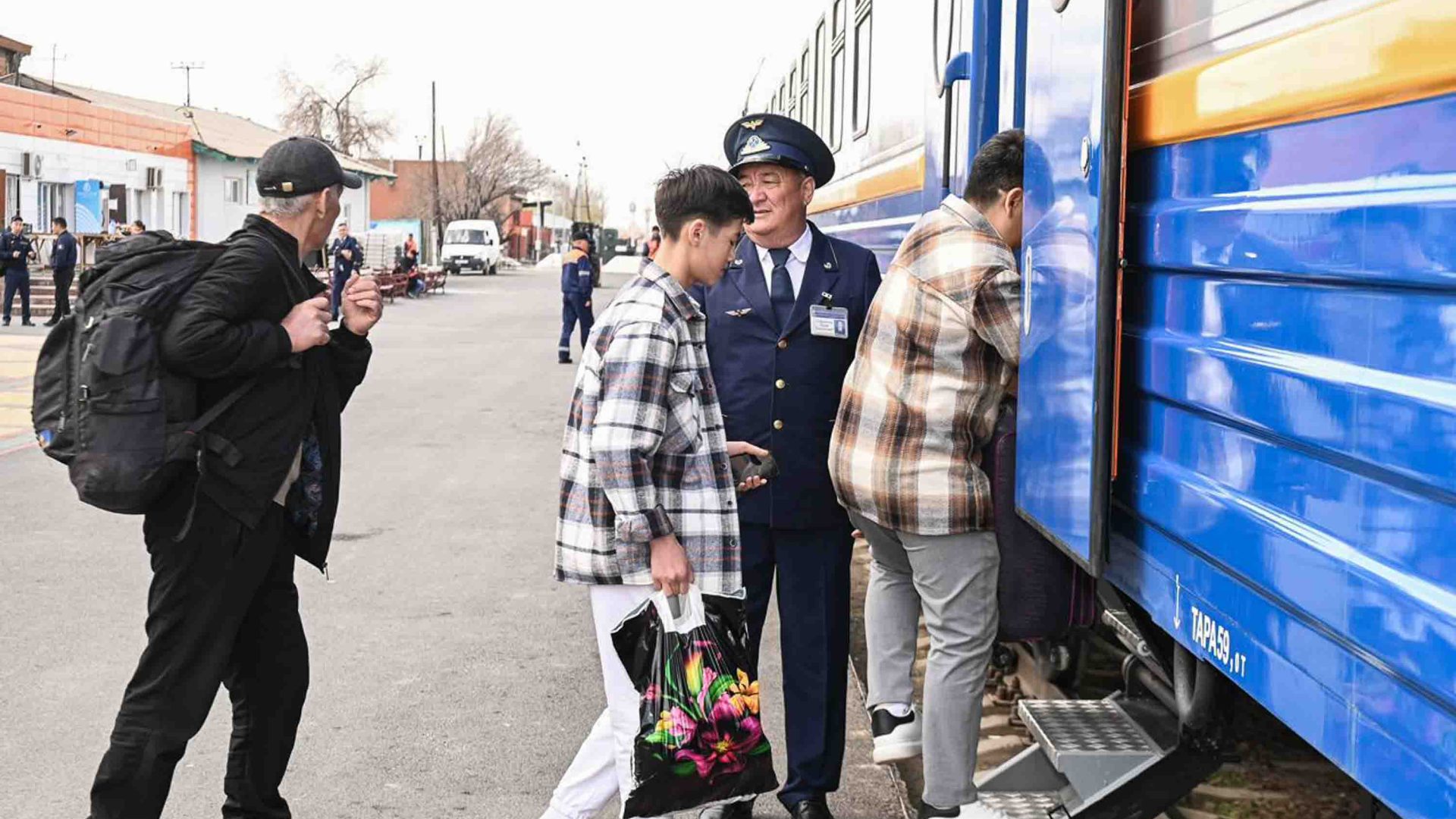 A station guard stands aside as people board a train.