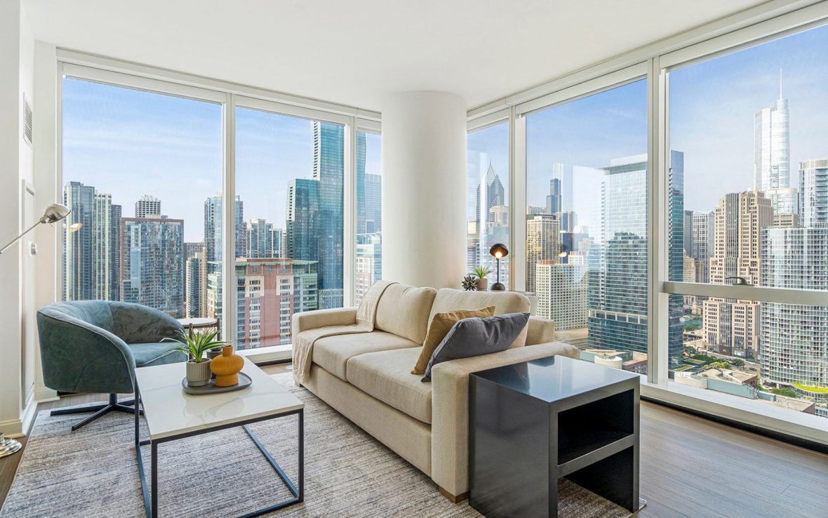 A sofa in a high rise apartment building with floor-to-ceiling views of Chicago.