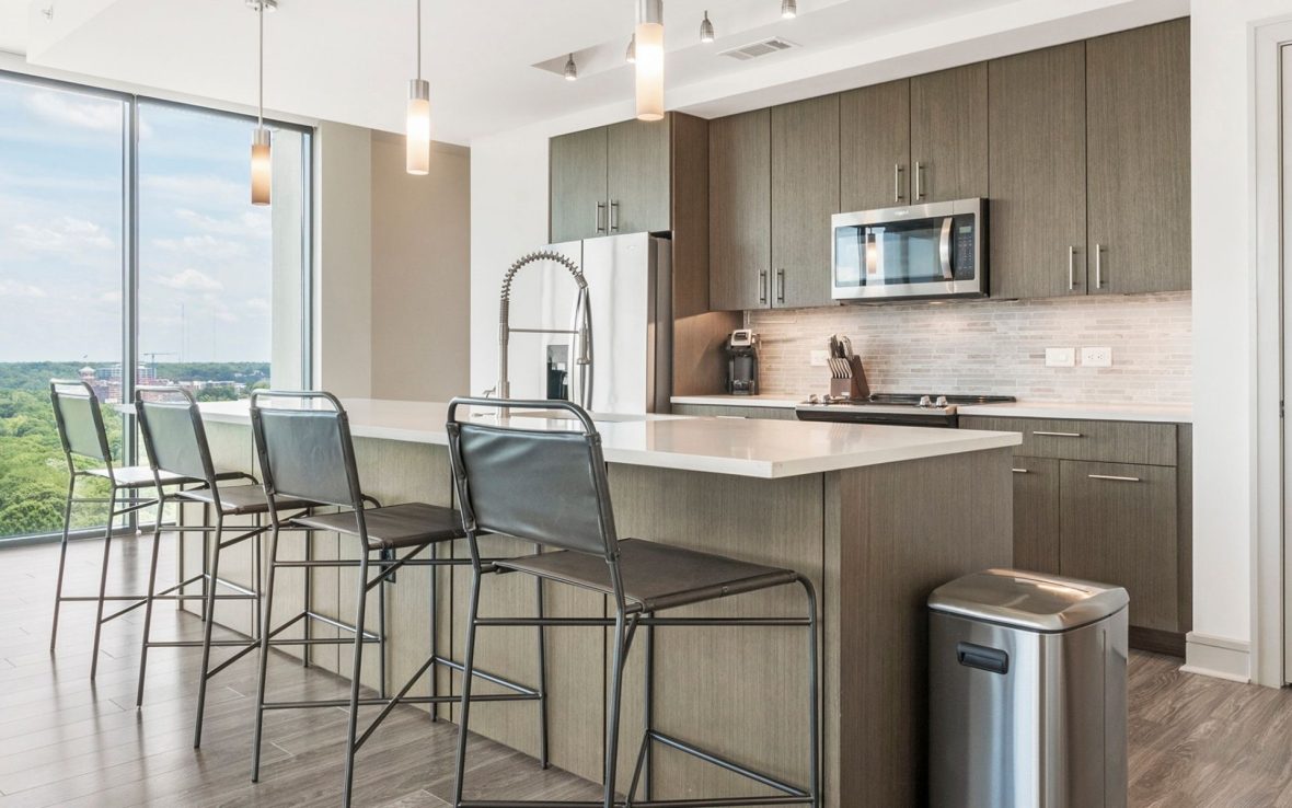 Photo of a sunny kitchen with an island with two tall chairs.