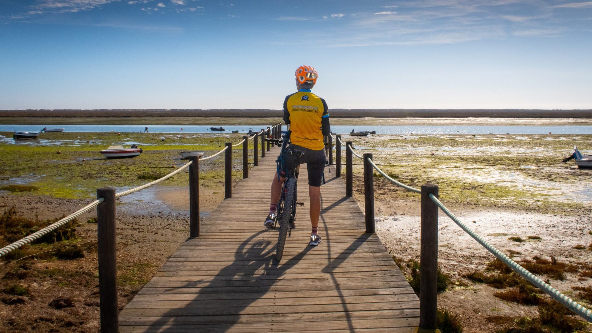Man in yellow rides down boardwalk.