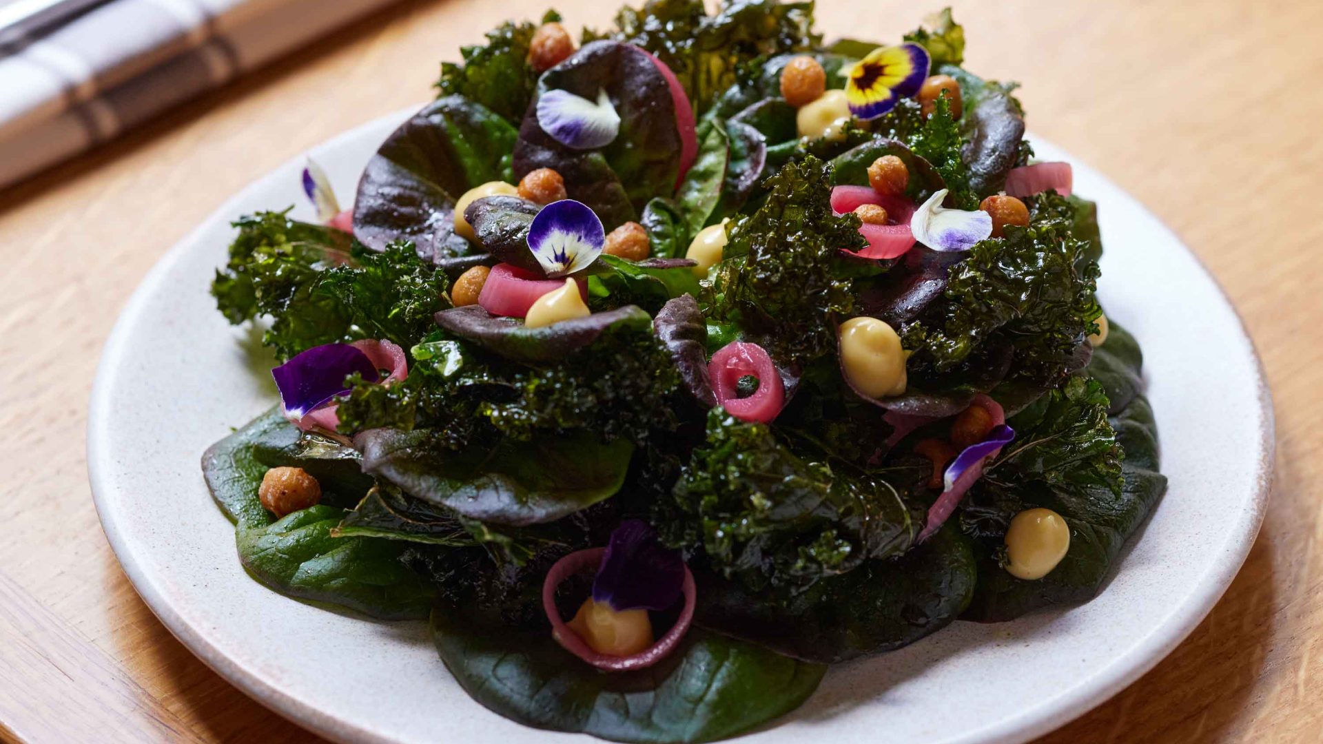A plate of kale and tomatoes on a table.