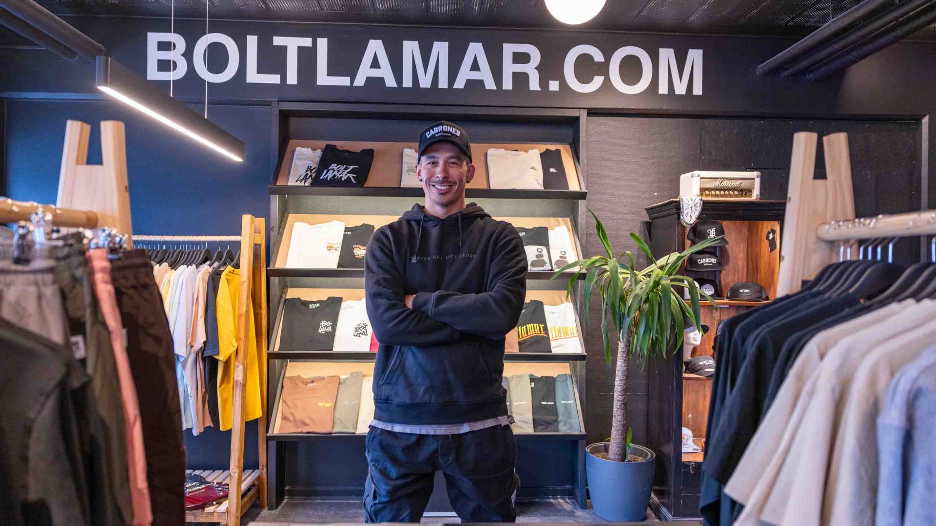 A man stands in a clothing store in front of the sign that reads 'Bolt Lamar'.