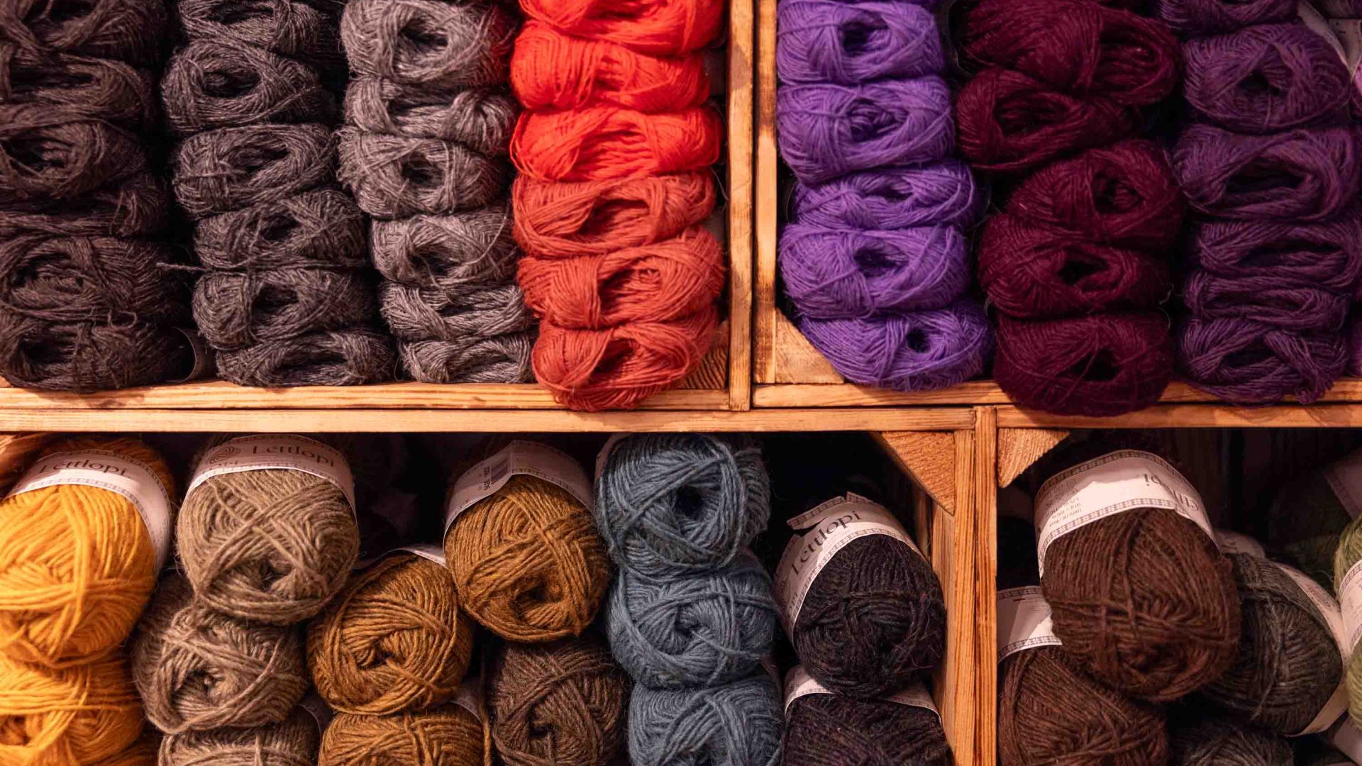 Stacks of colorful wool in wooden boxes.