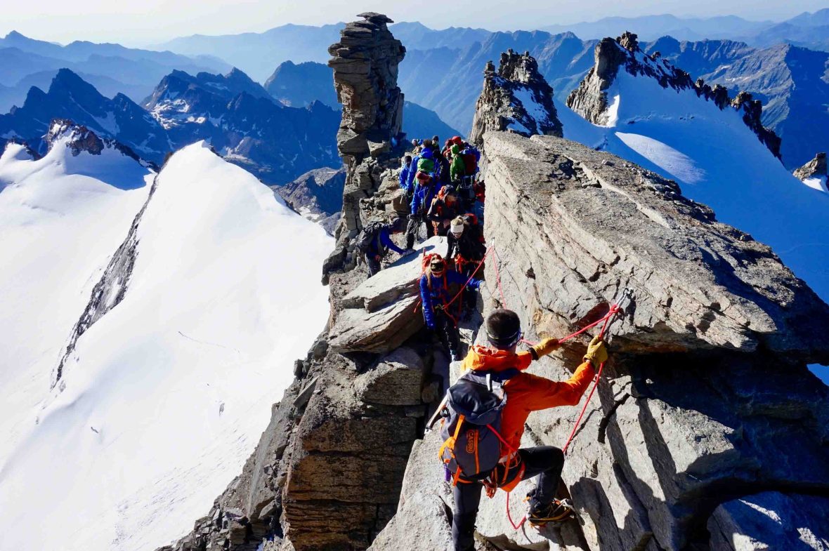A group of people with ropes practices mountaineering on a snowy mountain.