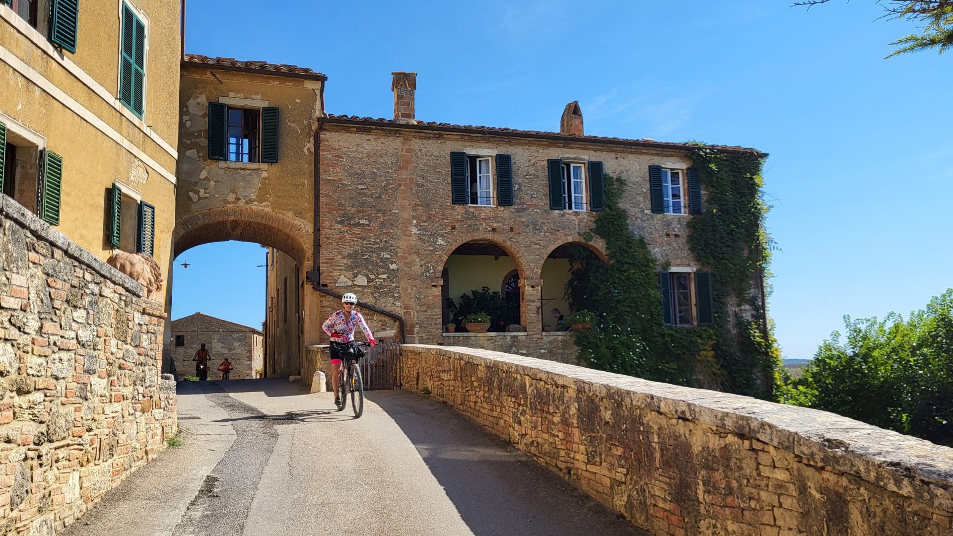 Cyclist rides through cobblestone village.