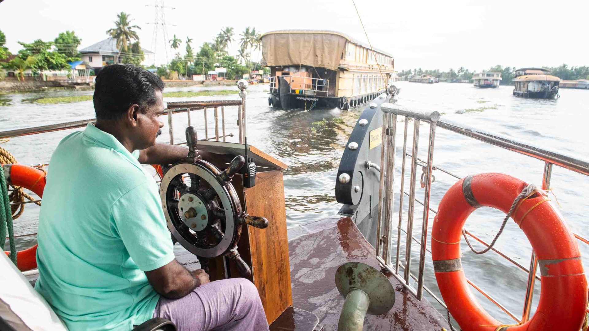 The Capitain drives the boat and looks at another boat in the water.