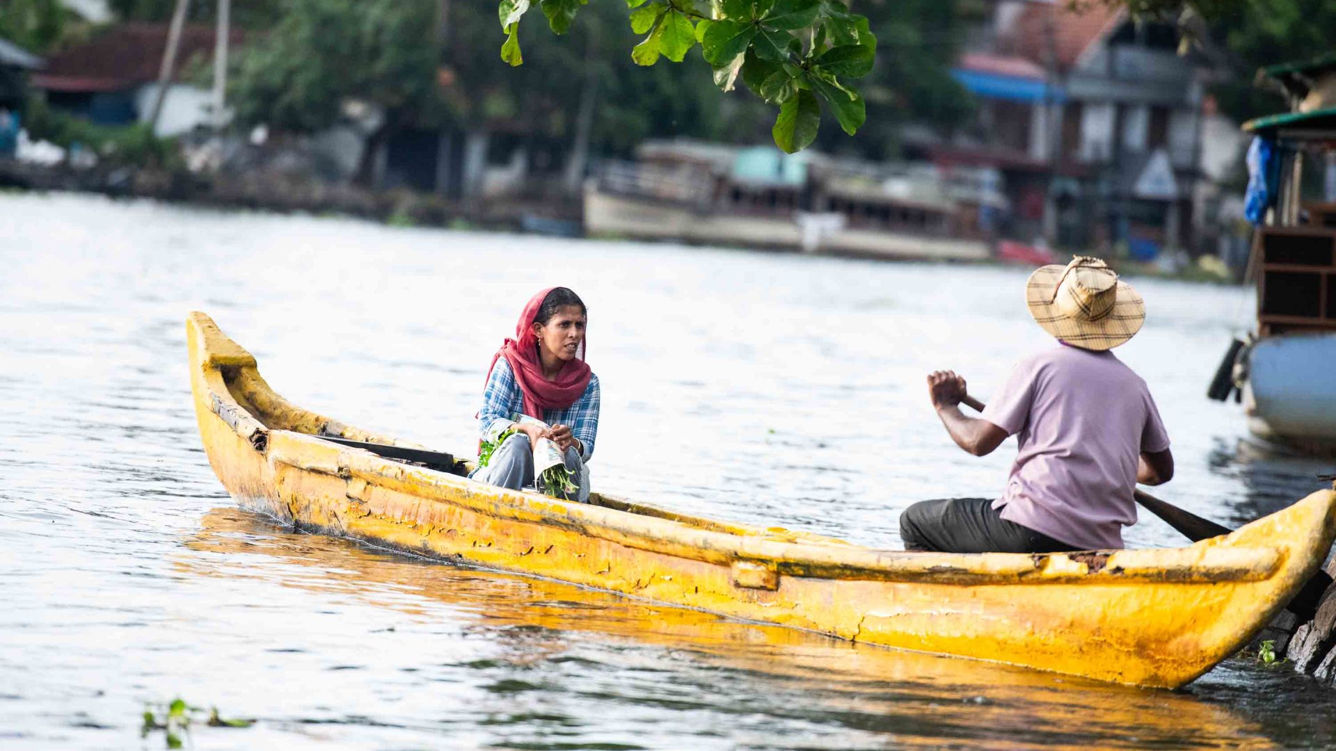 A man rows a woman in a small yellow canoe.