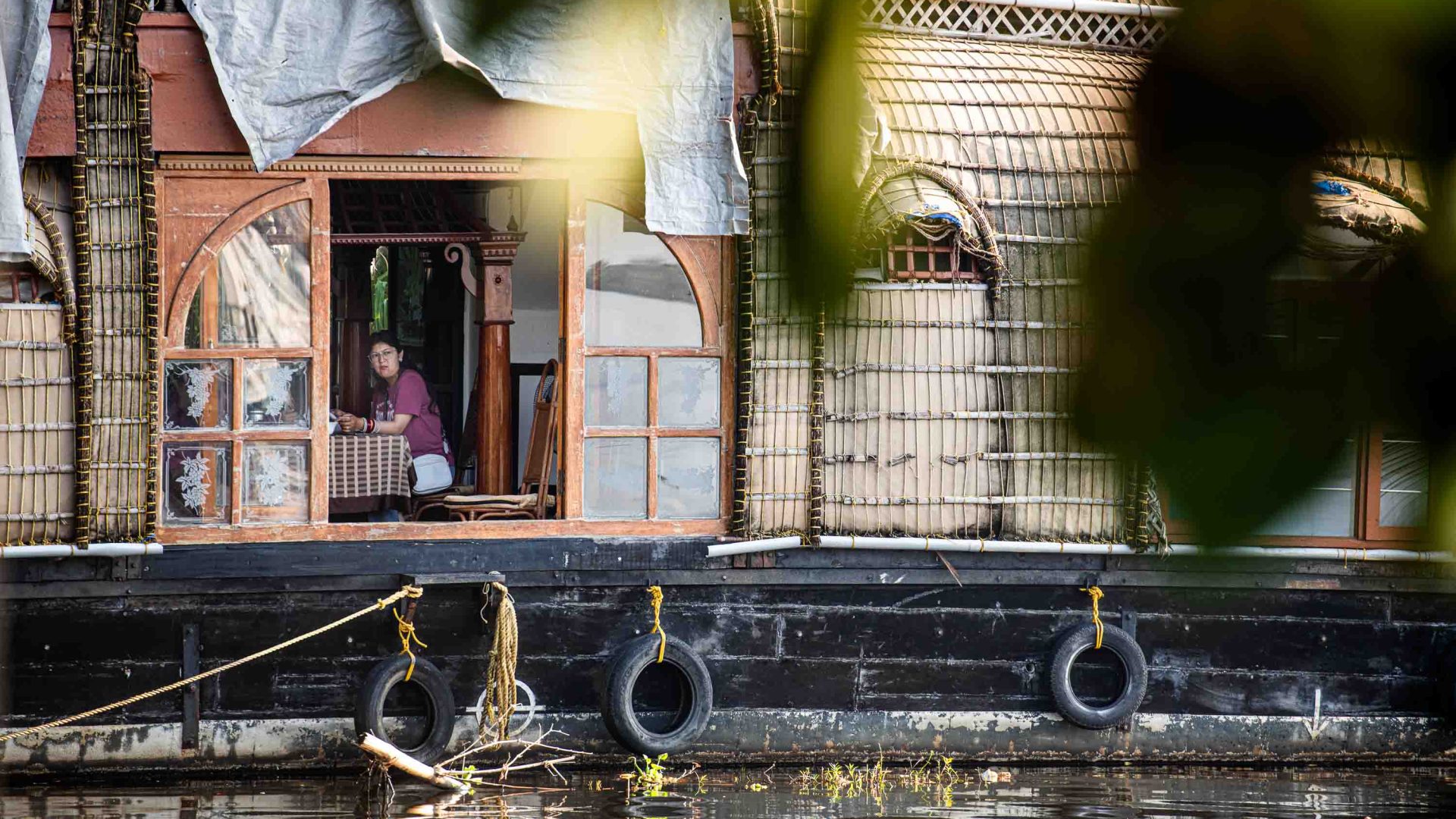 A woman is seen sitting at a table in a houseboat.