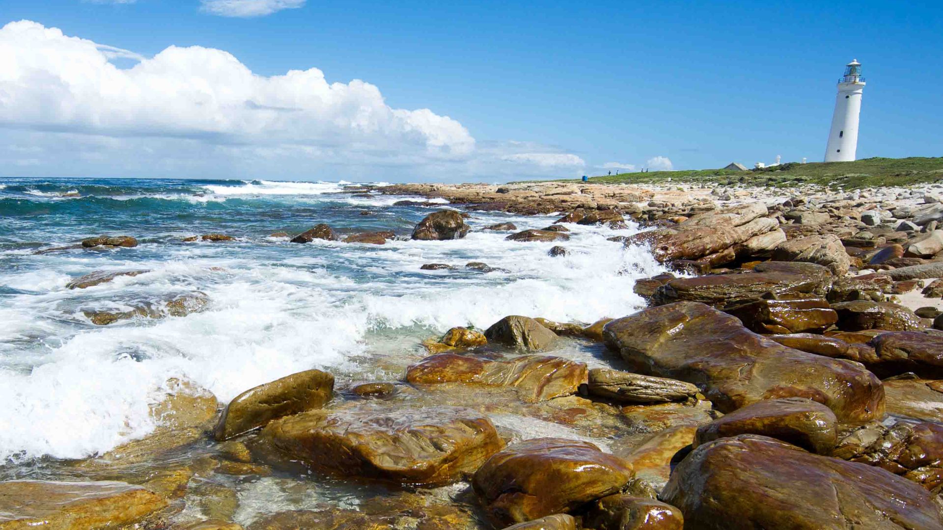 A lighthouse, rocks and the ocean.