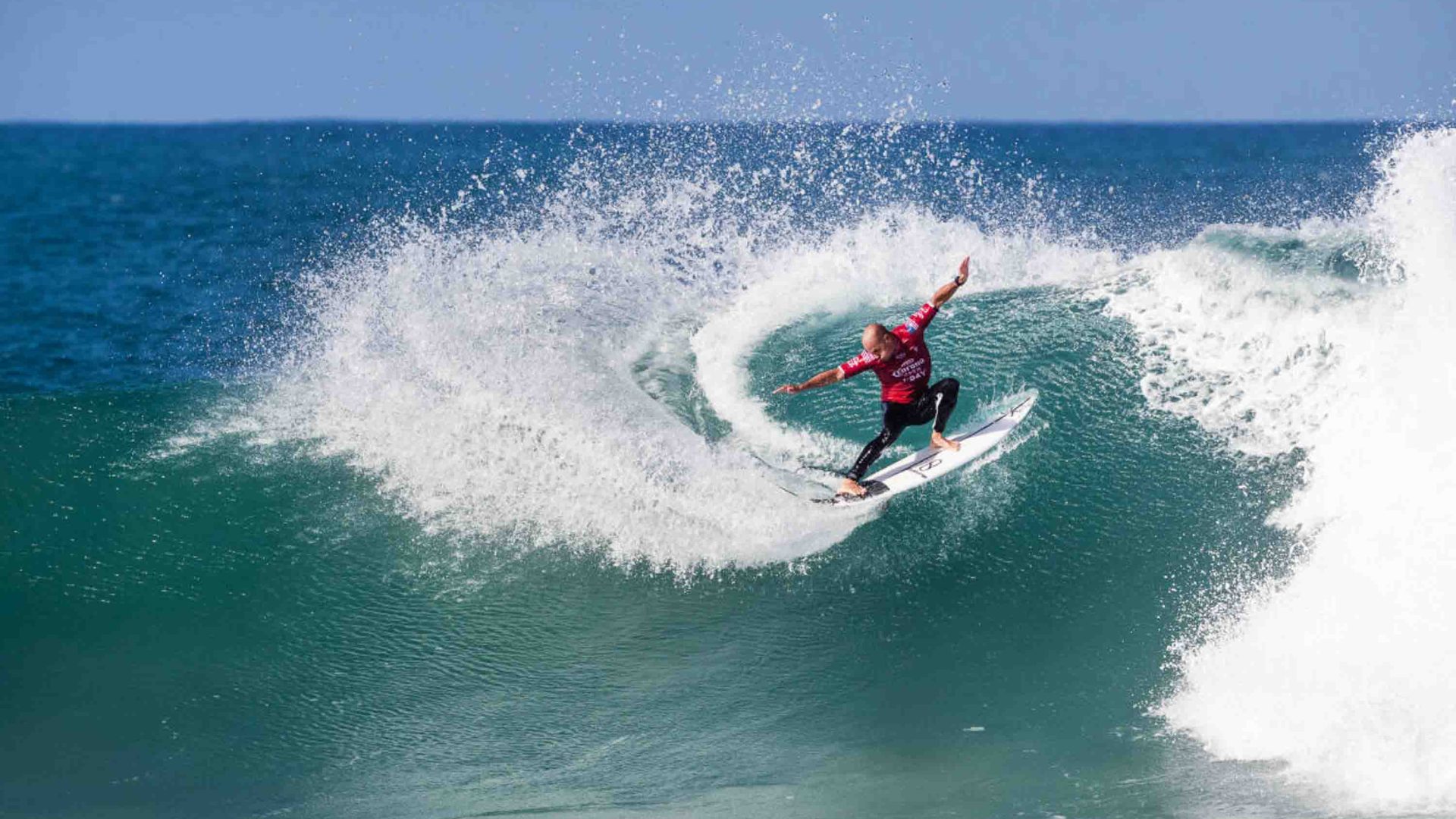 A man performs a turn on his surfboard while ona wave.