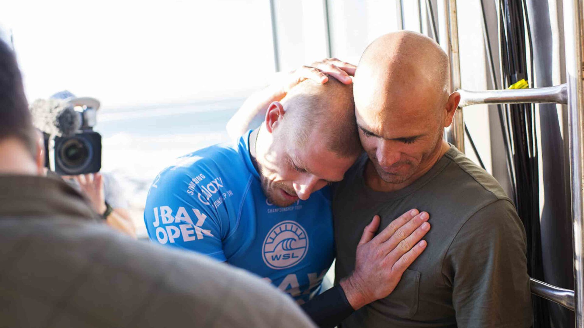 A man hugs another man to comfort him.