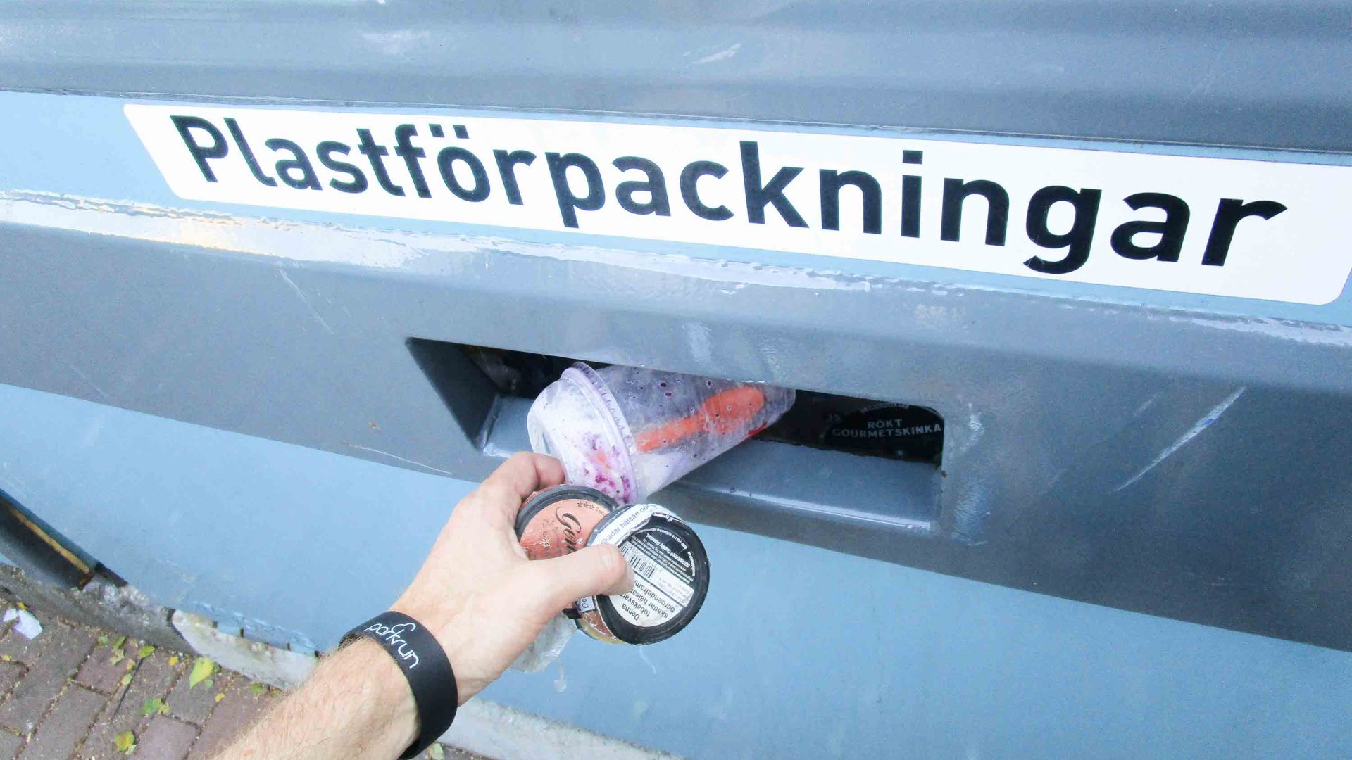 A hand puts plastic bottles in a recycling return bin.