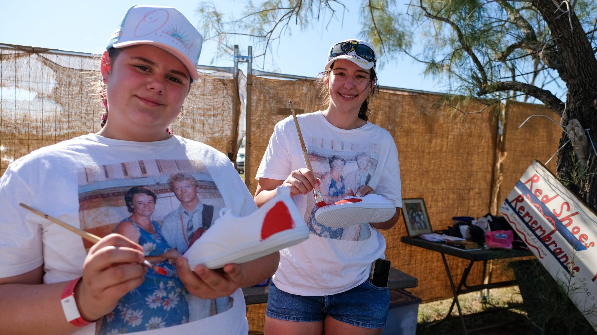 Two young girls paint white shoes red.