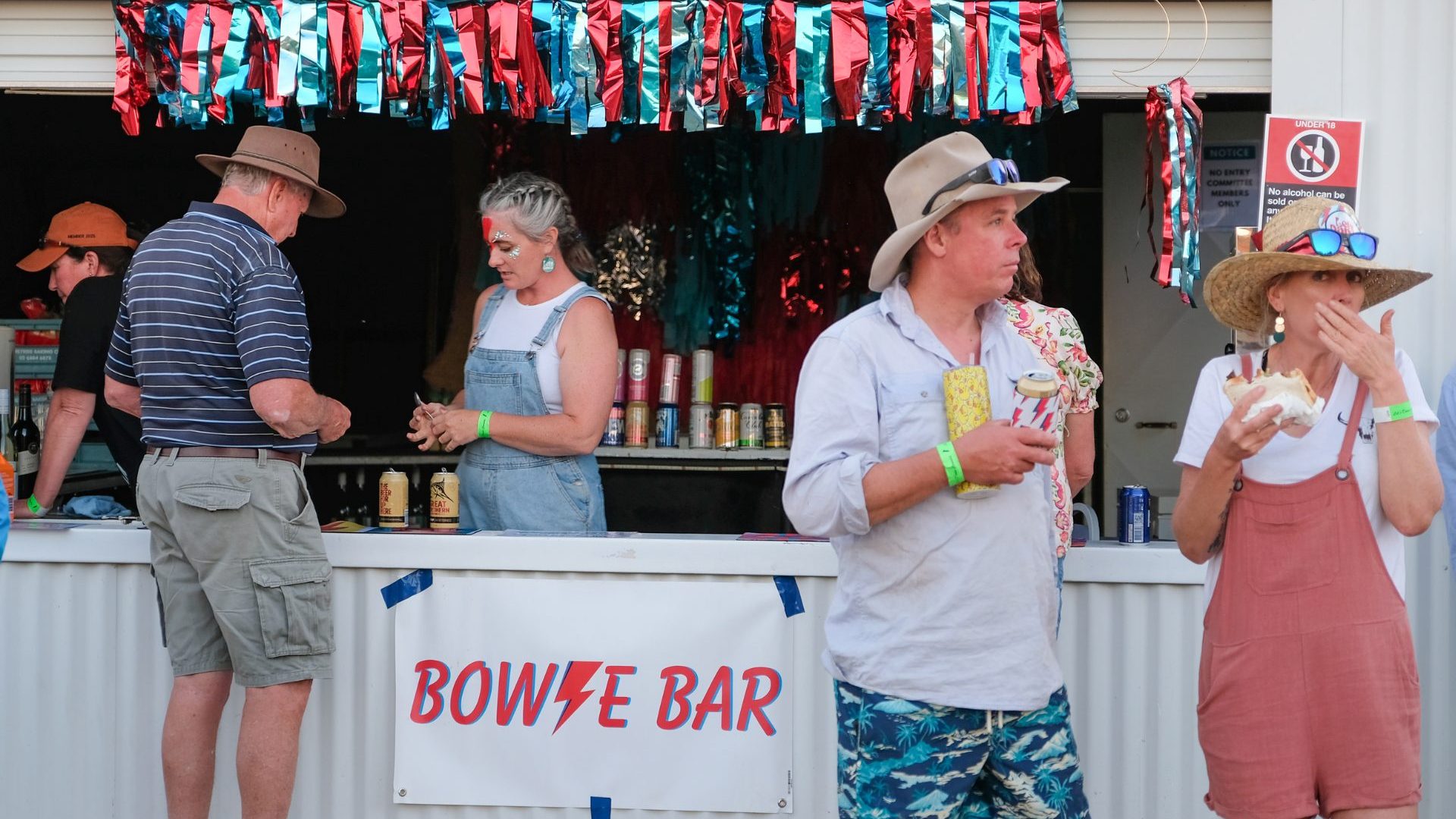 Four people lean against bar titled 'Bowie Bar'.