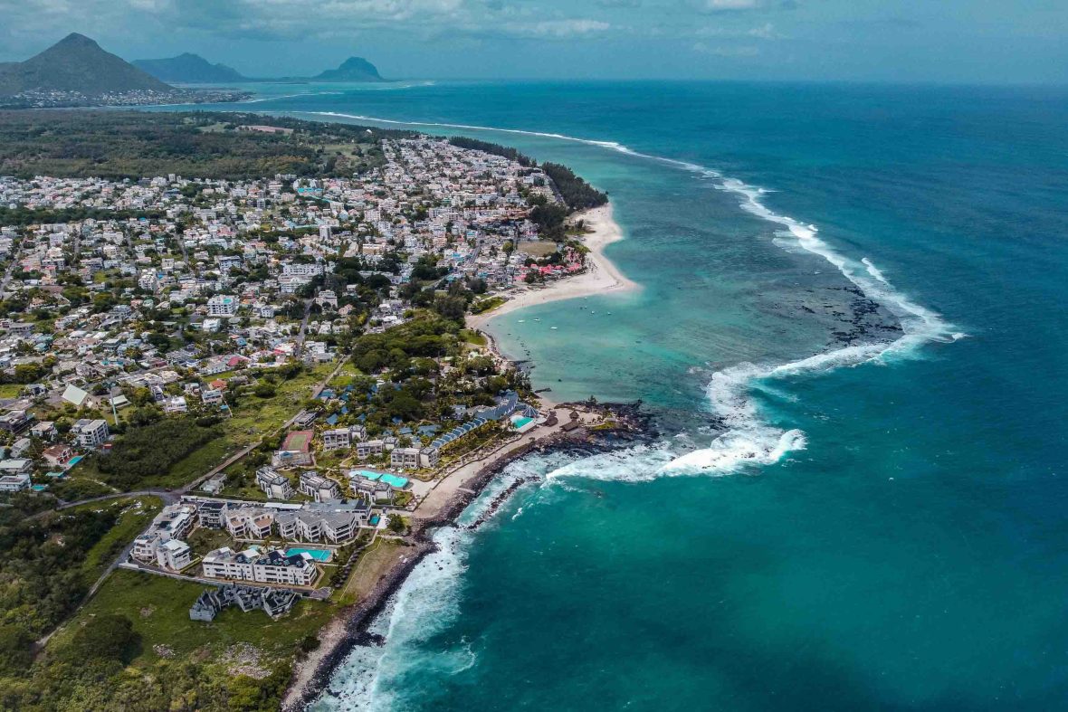 A stretch of coast with buildings along the edges of white sand and turquoise water.