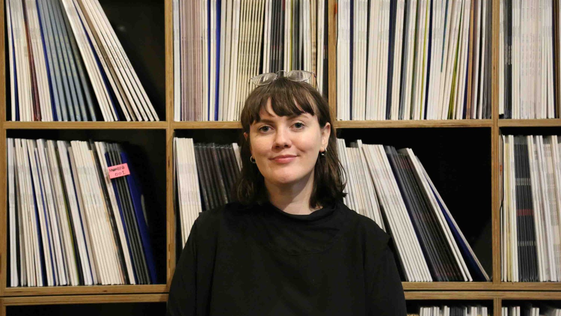 Woman stands in front of record wall.