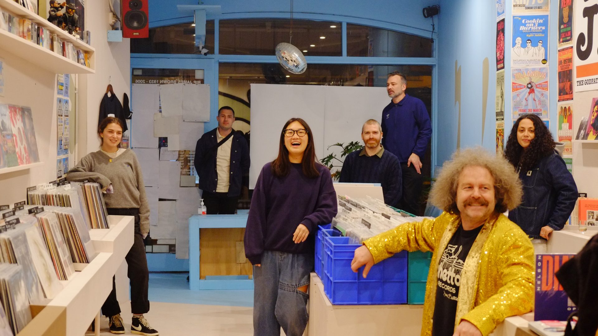 A group of people pose for a photo inside a record store.