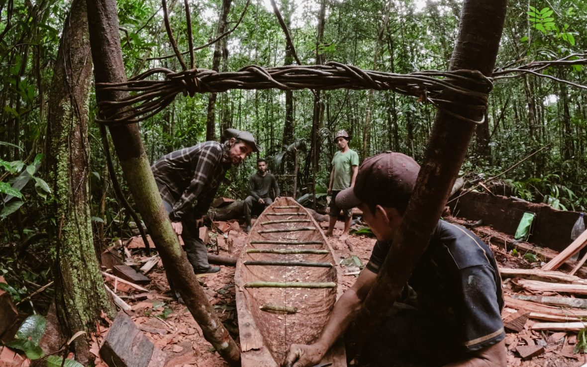 Three men build a dugout canoe