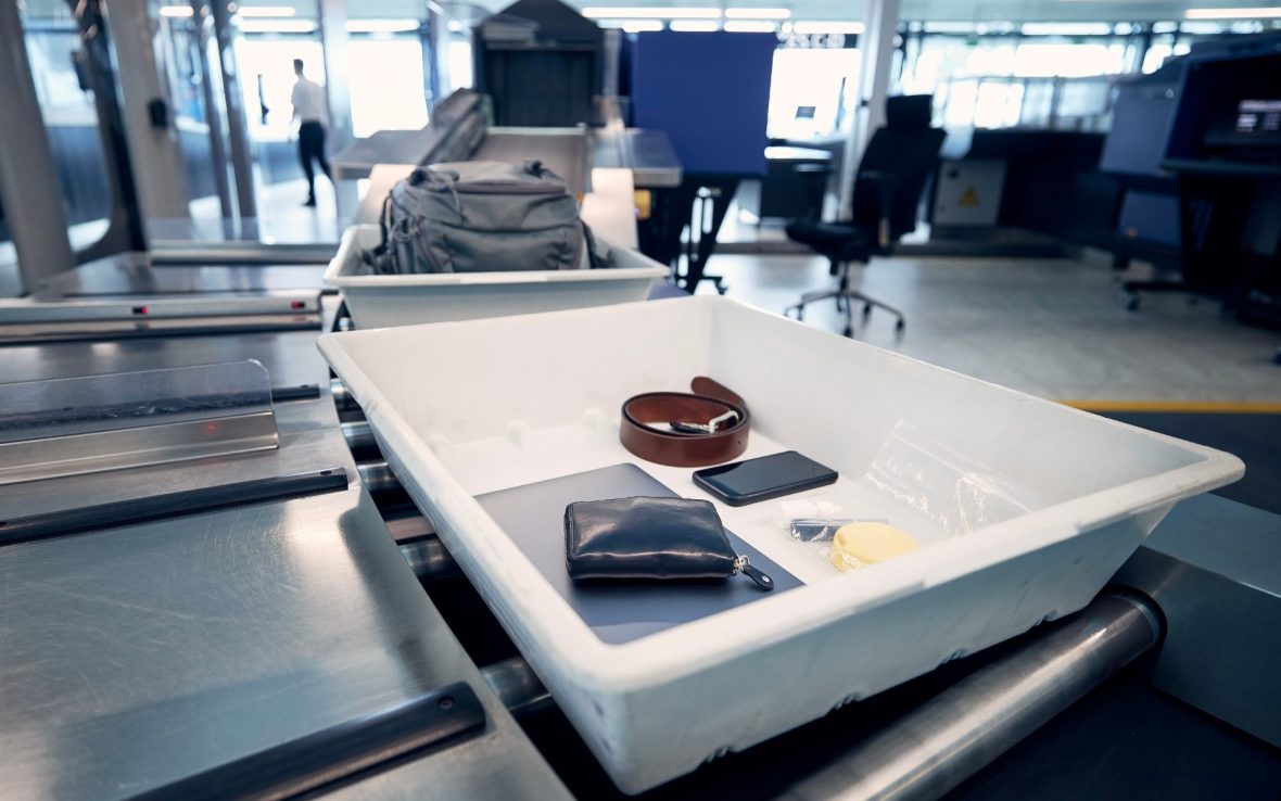 An tray holding a wallet, phone and belt goes through airport security scanners.