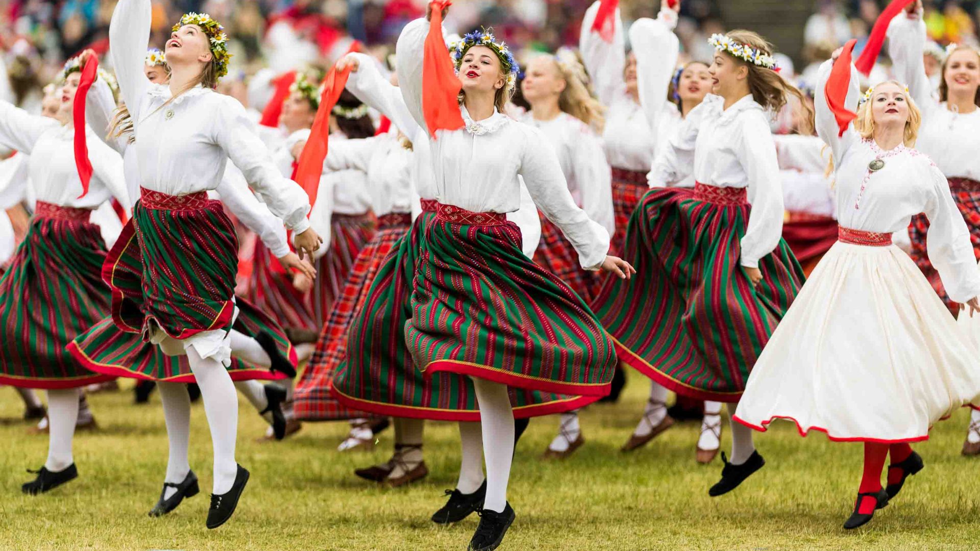Women in red and white dance in traditional clothing.