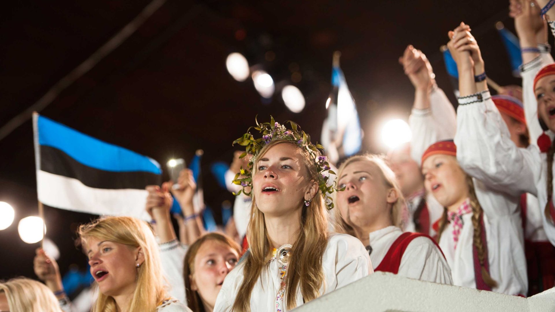 Women in traditional red and white clothes sing together.