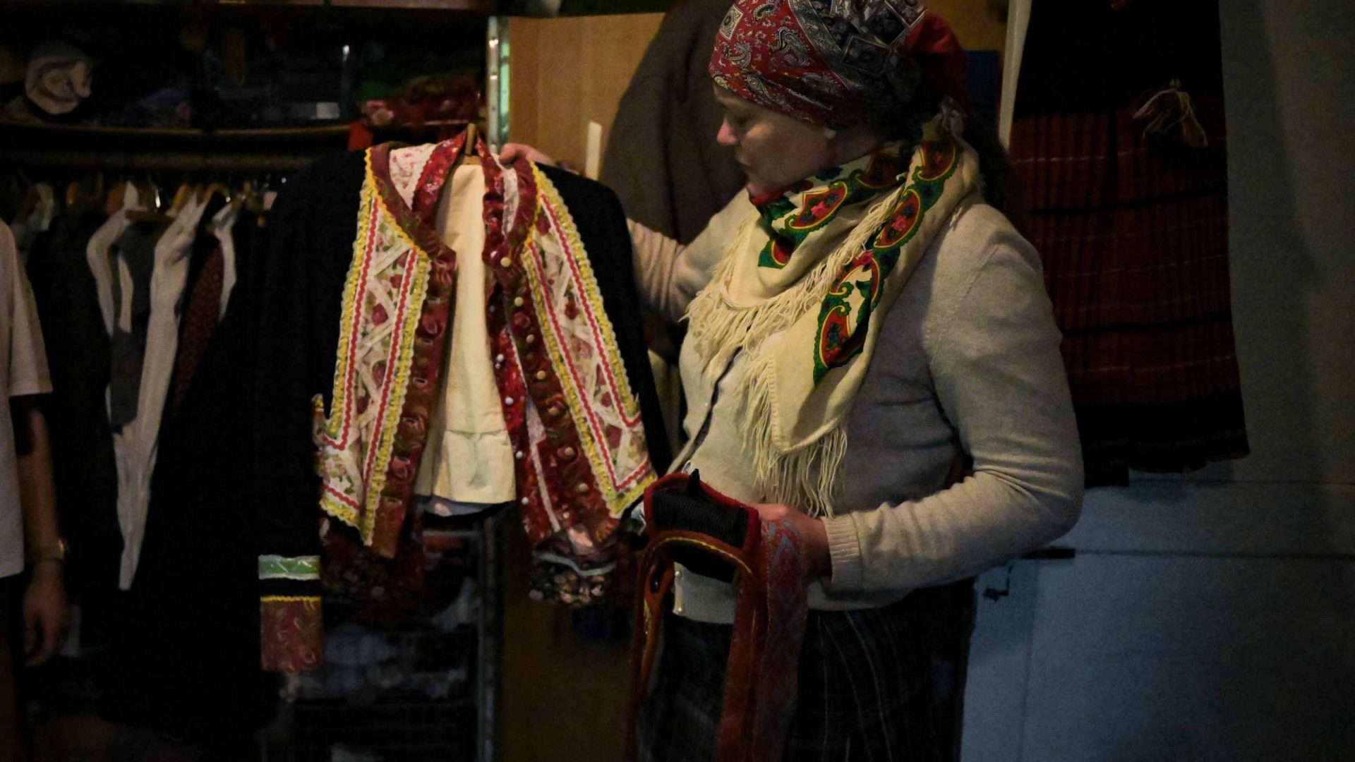 A woman holds up a traditional red and white outfit.