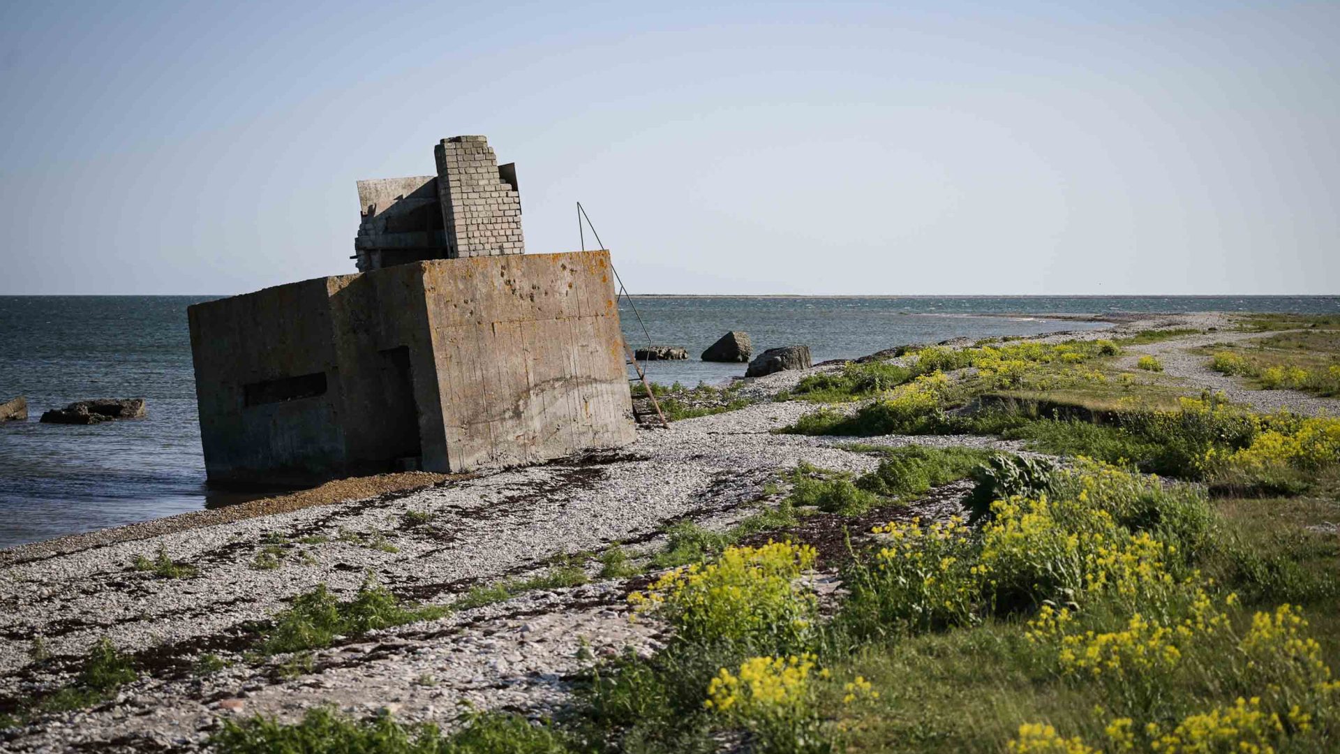 An old concrete bunker on a path next to the ocean.