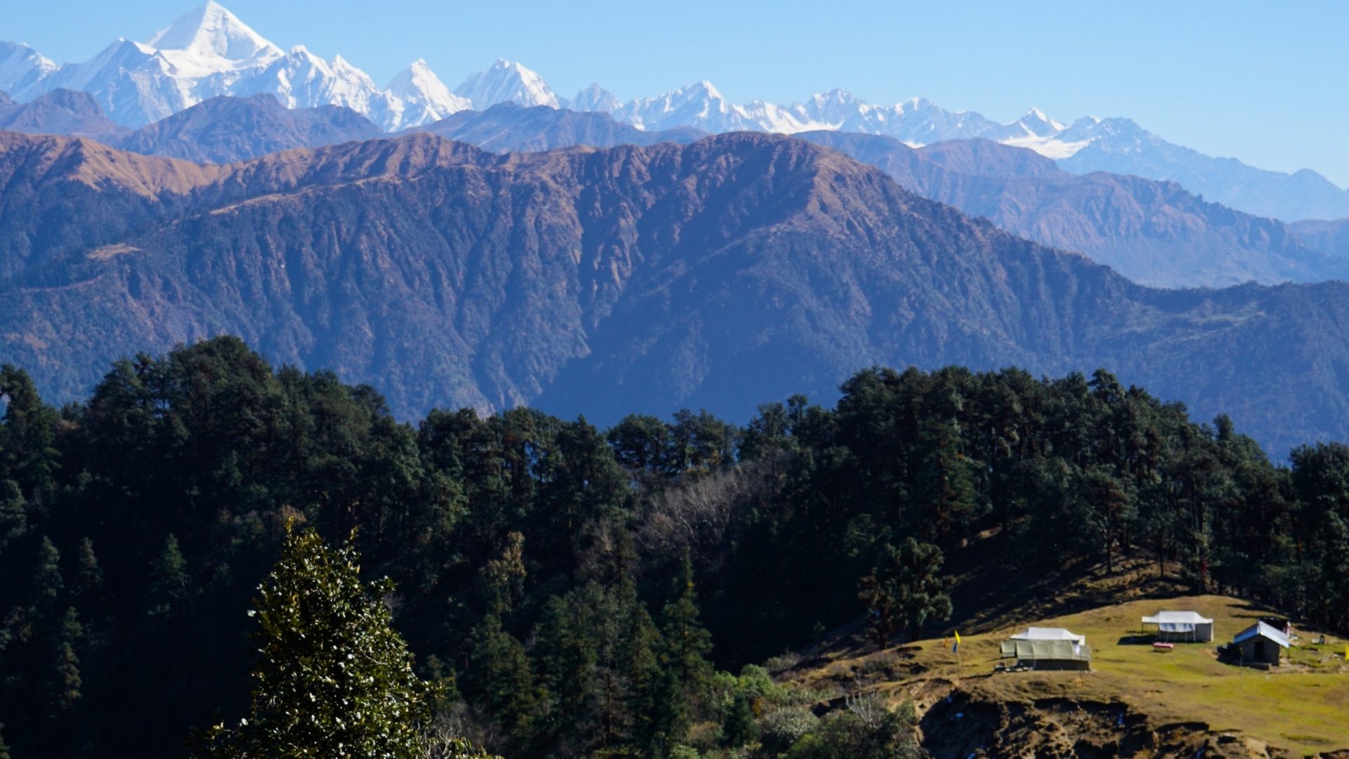 A view of a mountain range with villages and forest in the foreground