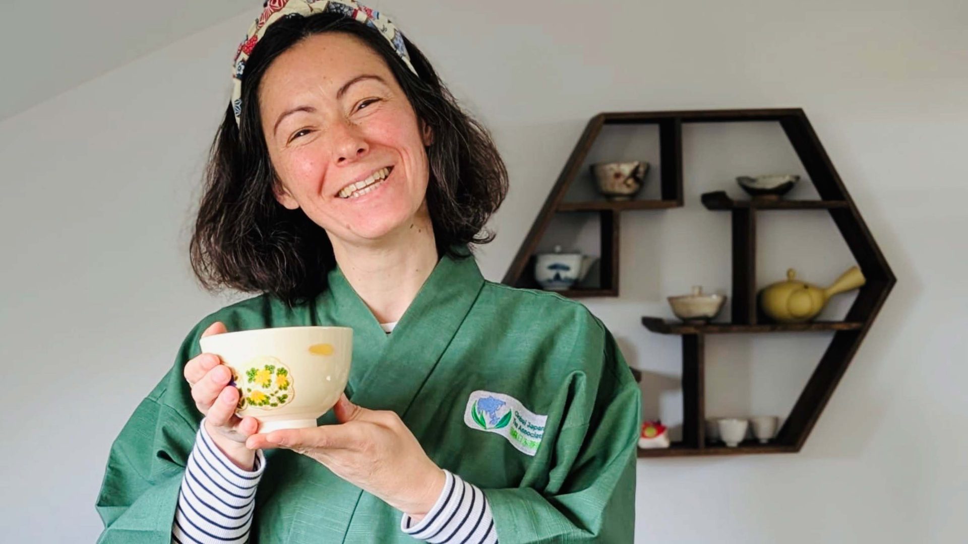A woman smiles as she holds a tea cup.