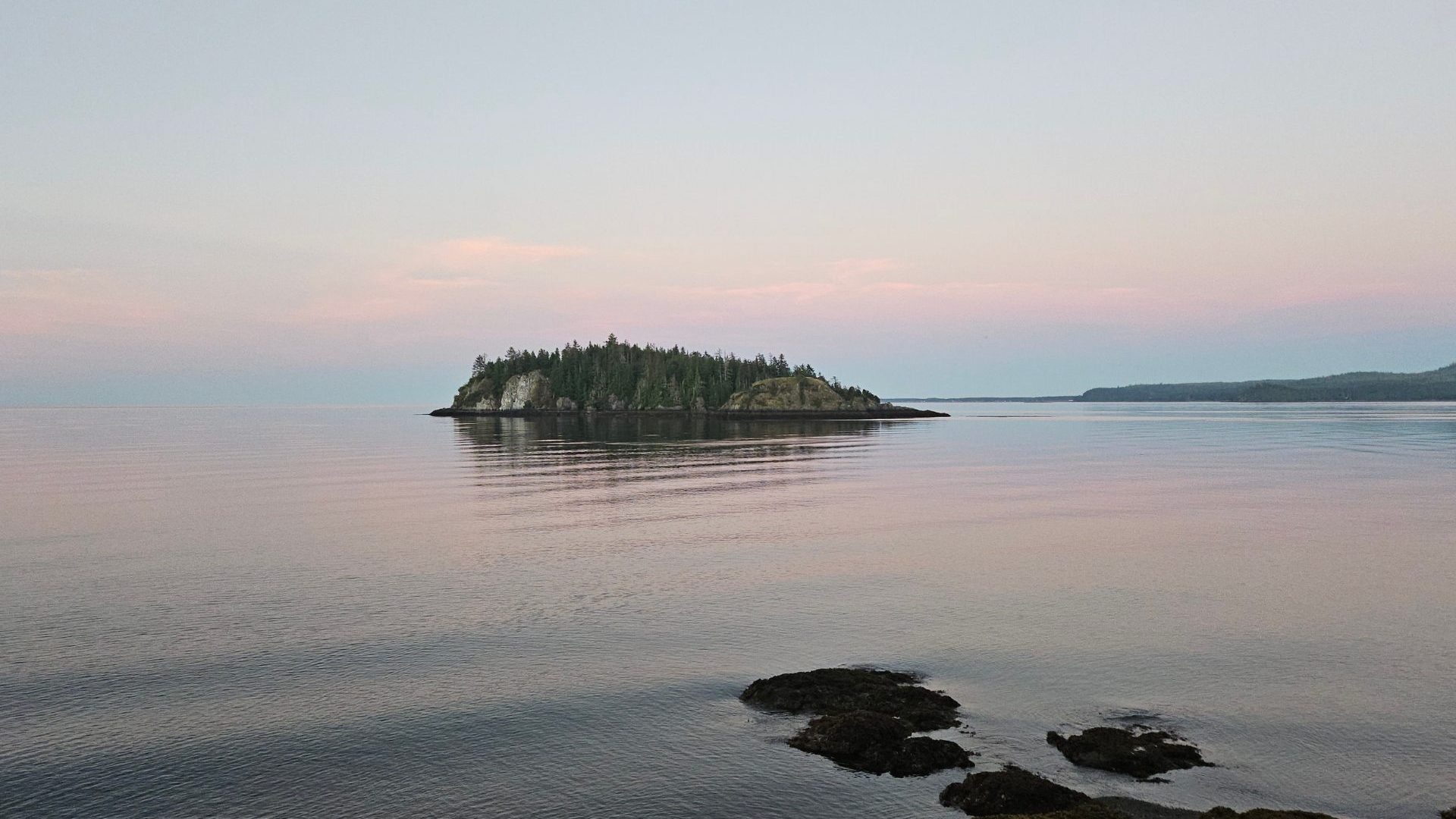 Pastel pink and blue sunset over water and small island
