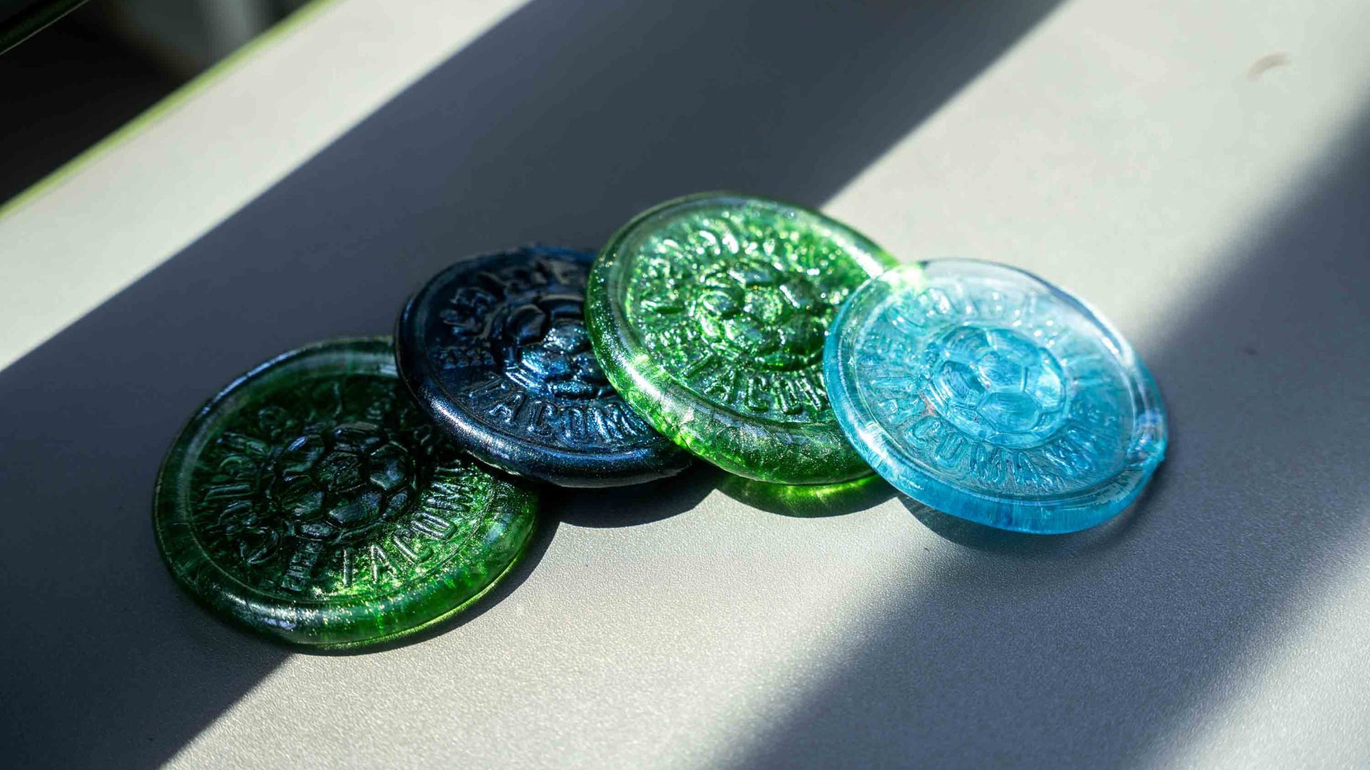 Glass medallions in green and blue on a surface.