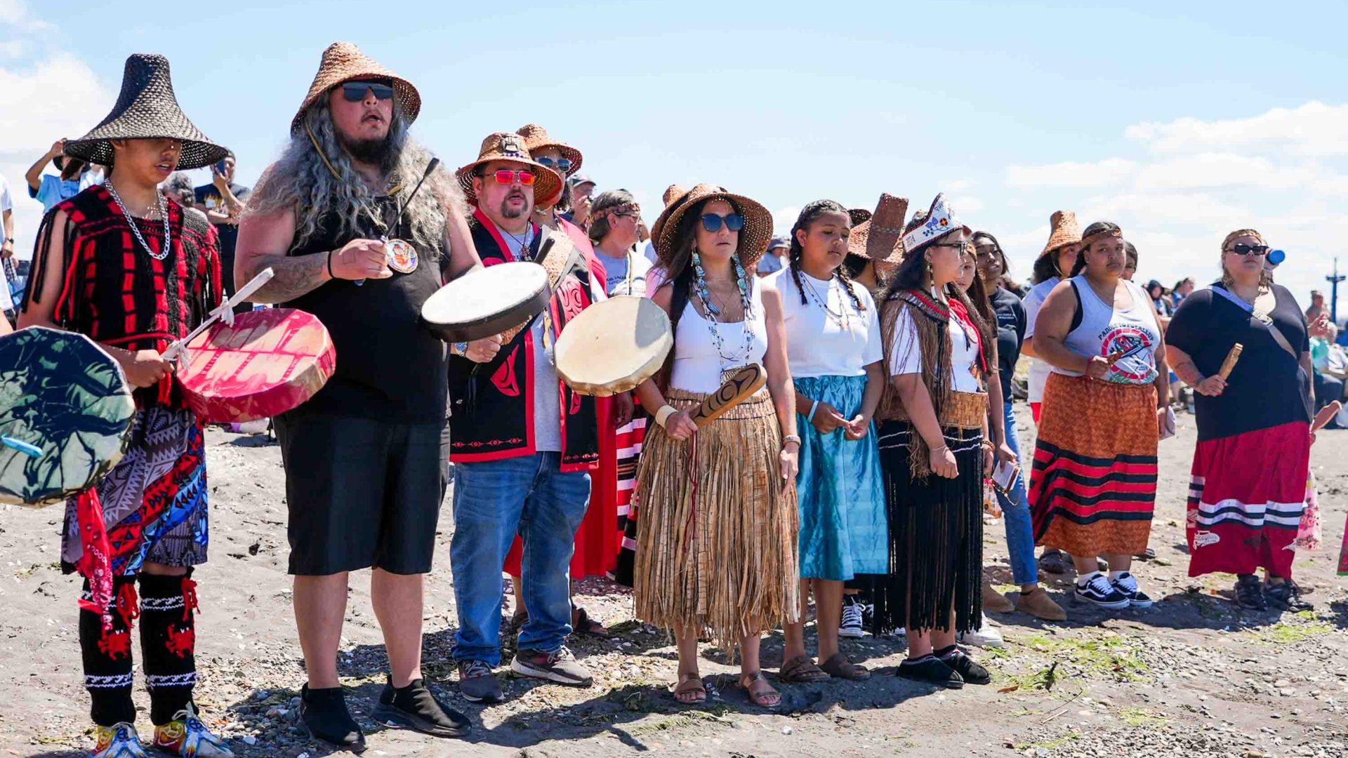 People stand on a beach and play instruments.
