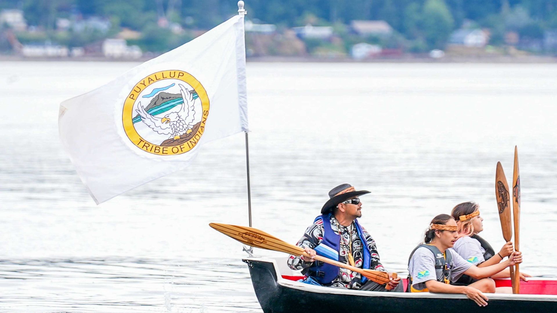 People in a boat with a flag of their tribe.