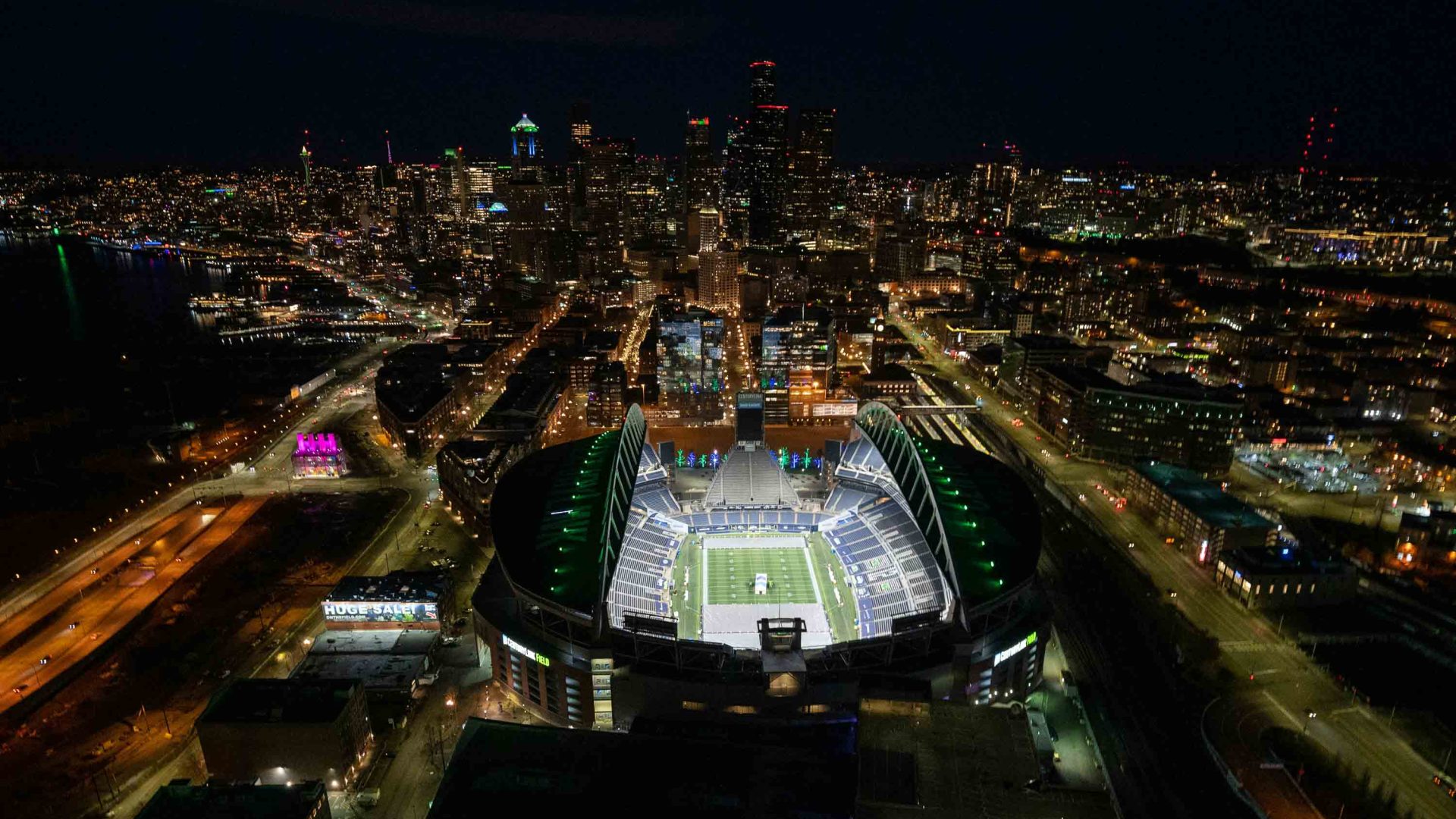 A drone photo of a stadium surrounded by city at night.