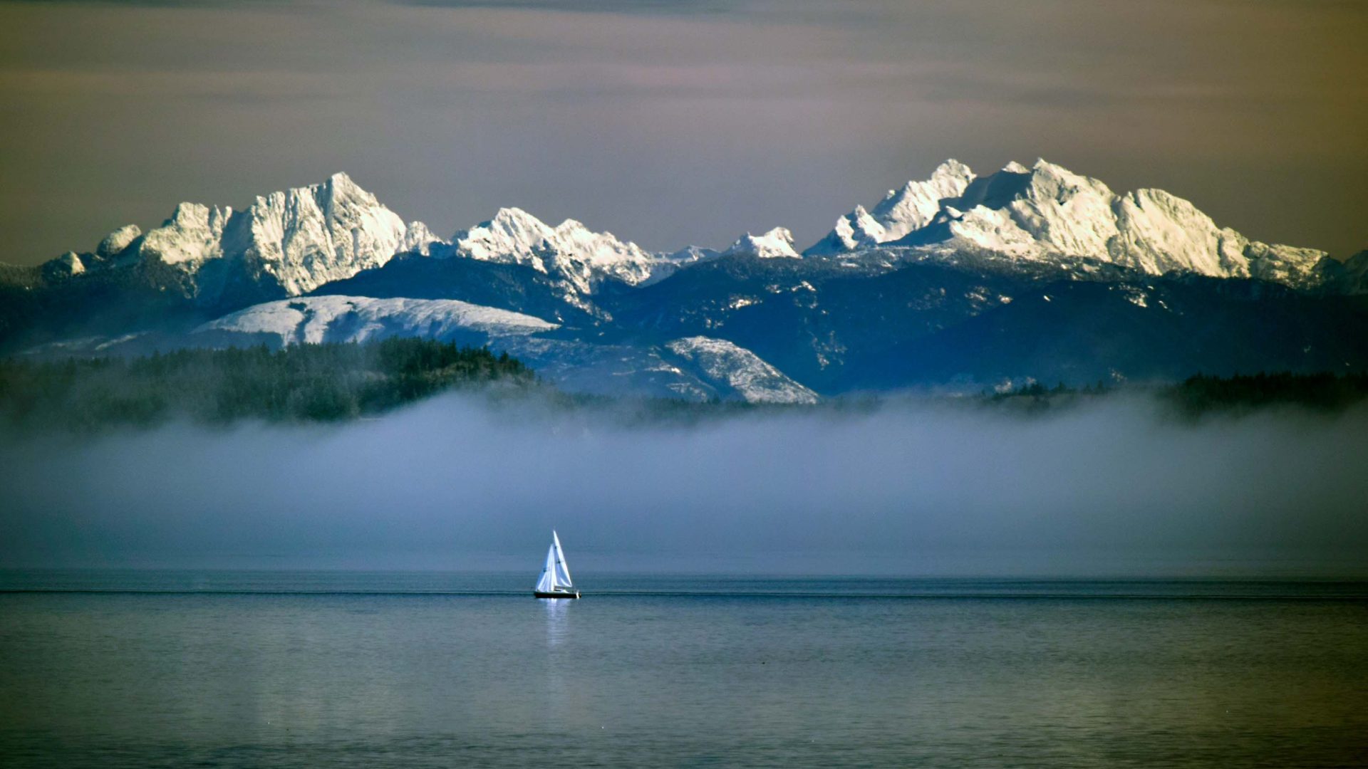 A boat in front of snowy mountains.