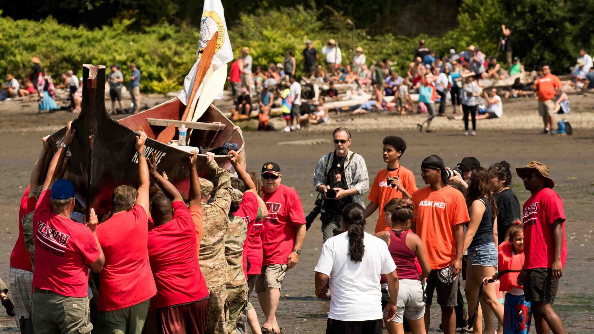 A number of people competing in a boat race carry the boat to shore.
