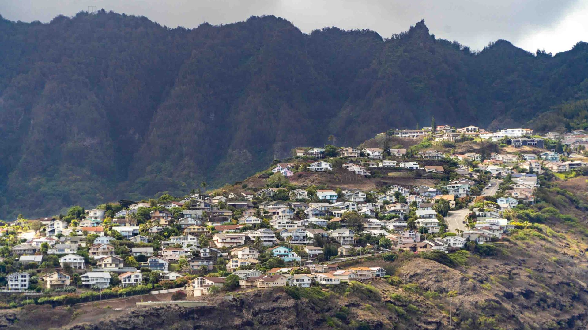 Houses on a hill backed with mountains.