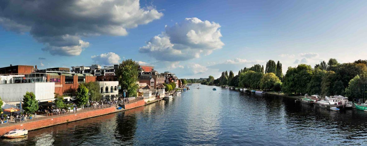 A wide shot of a river with buildings and trees on the shores.