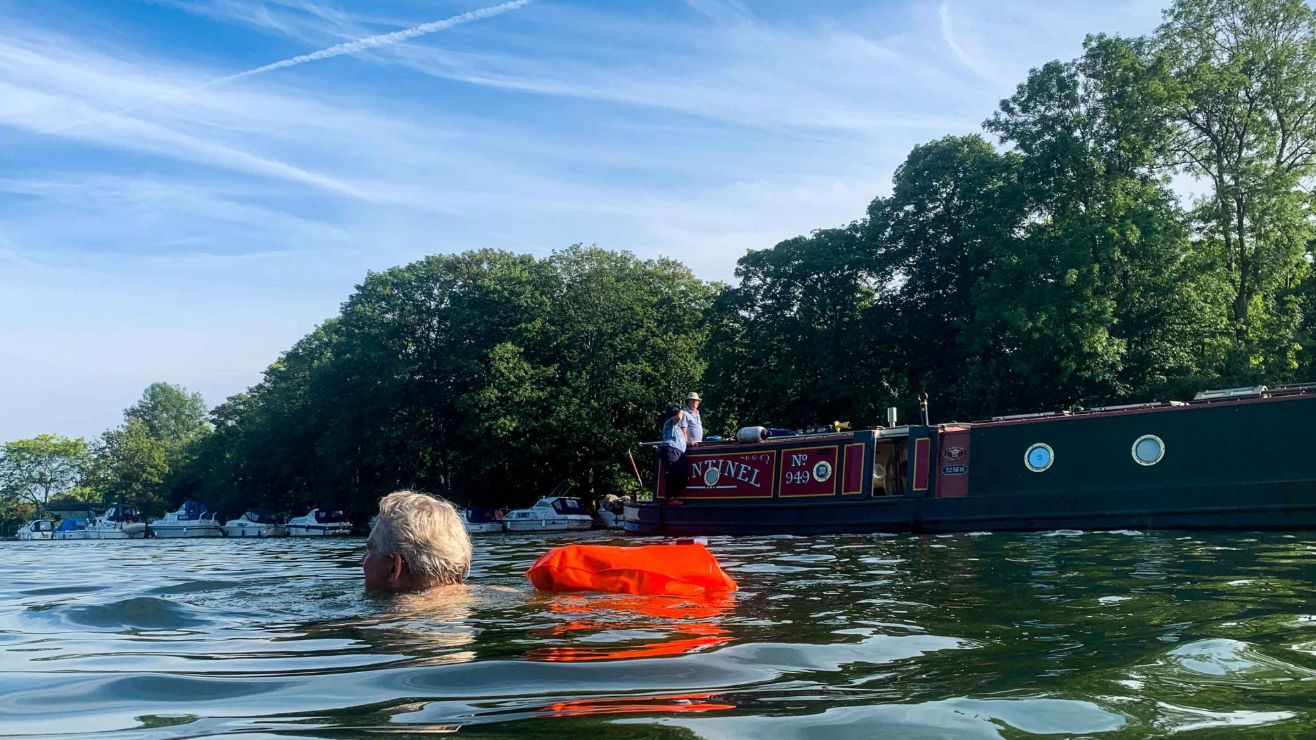 A man swims in the River Thames, not far from a canal boat.