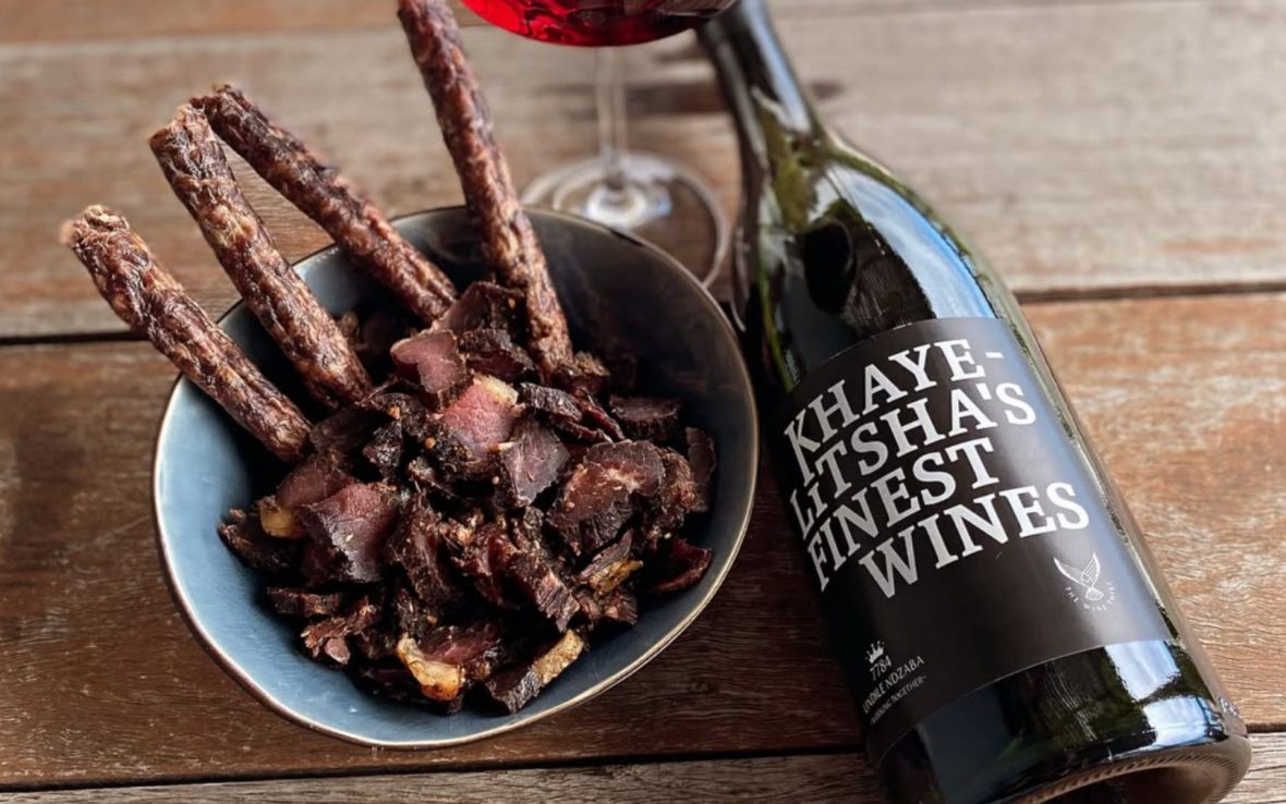 Bowl of dried meat next to bottle of wine.