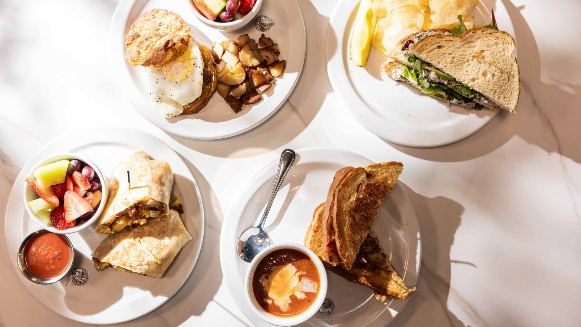 A photo of several plates of food including wraps and sandwiches.