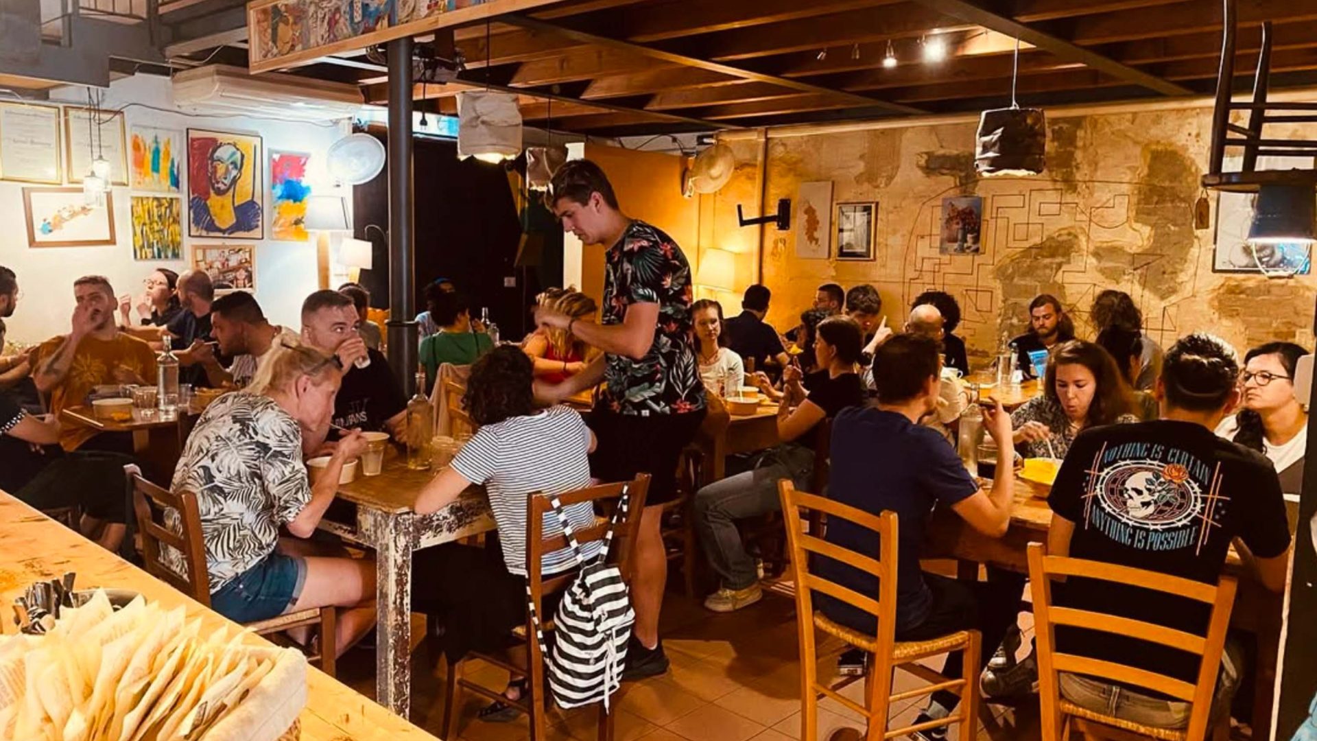 A waiter serves a table of people inside a busy cafe.