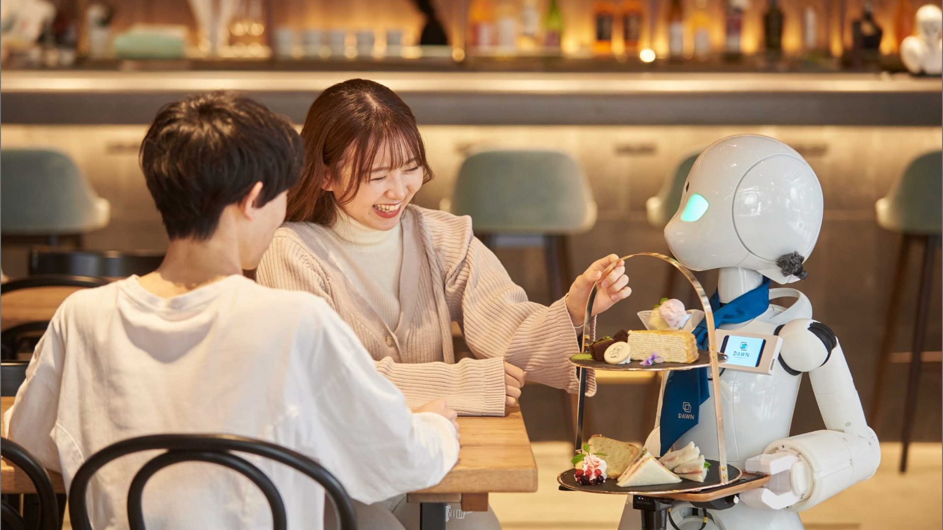A robot serves a man and a woman at a table.